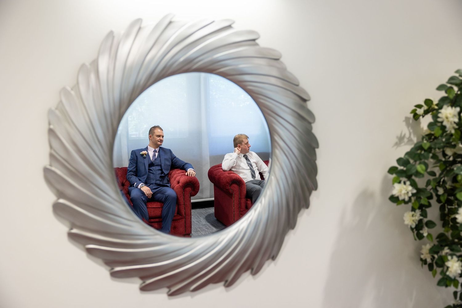A creative mirror reflection captures the groom and best man waiting, a quiet, anticipatory moment before the ceremony begins.