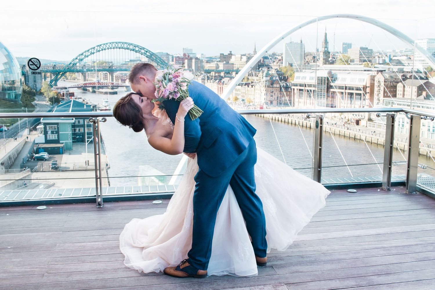 Bride and groom dip kiss at Baltic Newcastle, iconic Tyne Bridge backdrop, romantic North East UK wedding photography on the Quayside