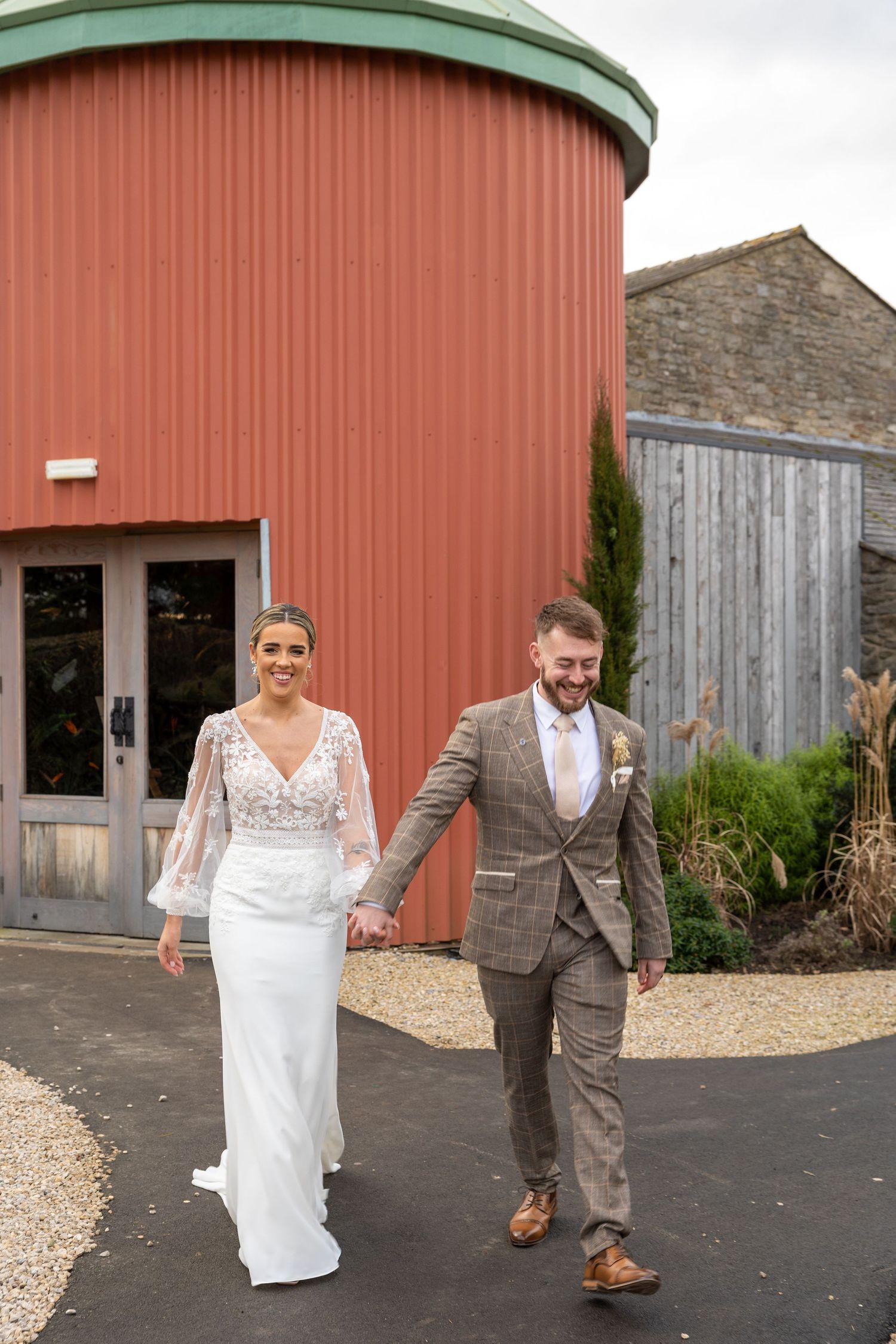 Bride and groom walk hand in hand at Runa Farm, rustic North East UK wedding venue with stylish barn setting and countryside charm