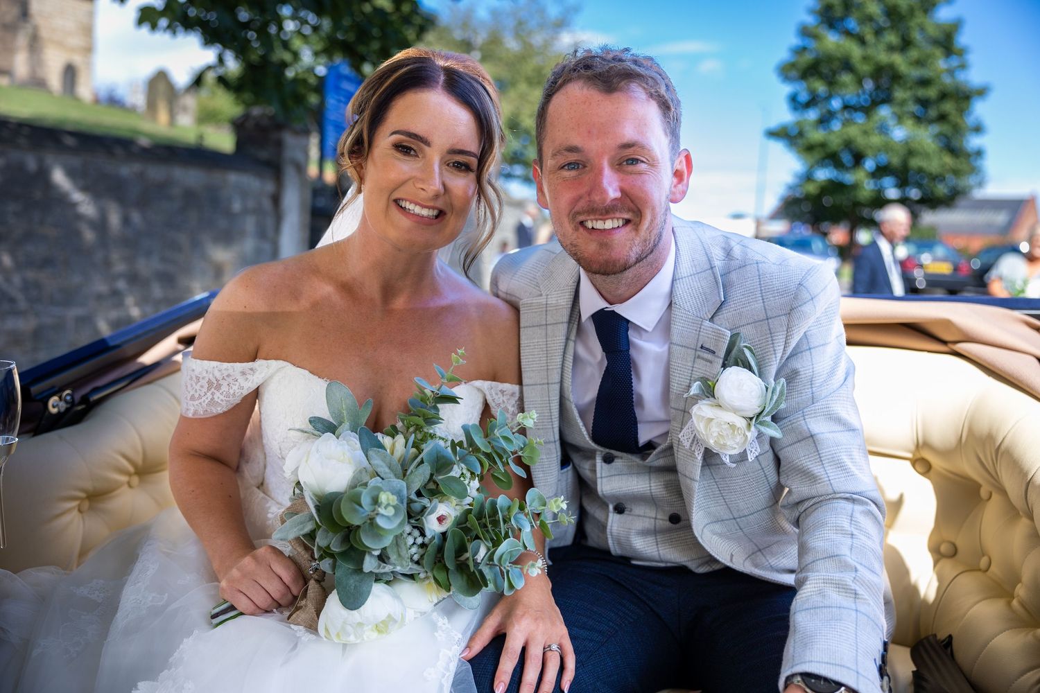 Bride and groom in wedding car, smiling couple, romantic UK wedding portrait, bouquet detail, just married moment