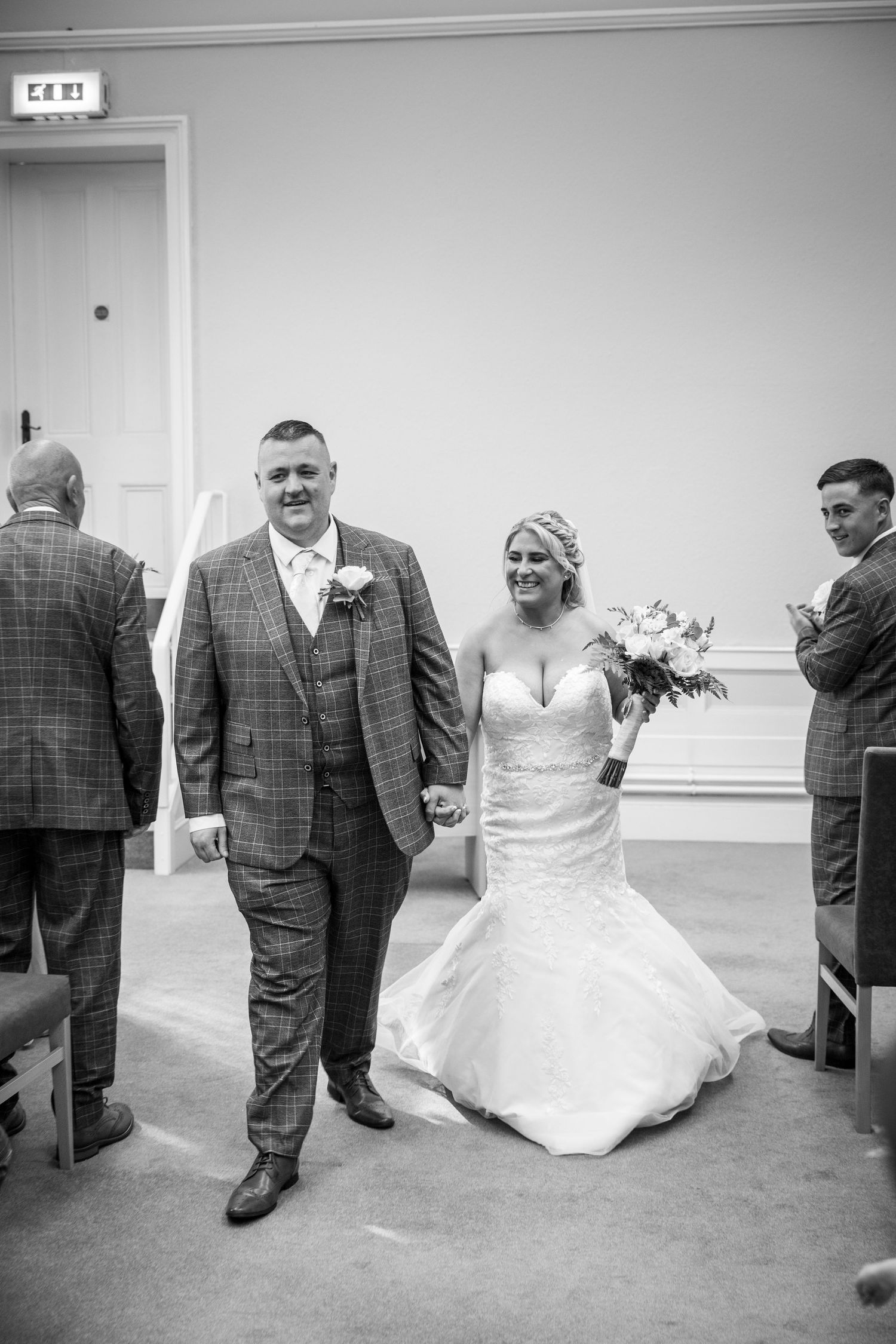 Bride and groom walking down aisle after ceremony, joyful just married moment, black and white wedding photography, candid celebration scene