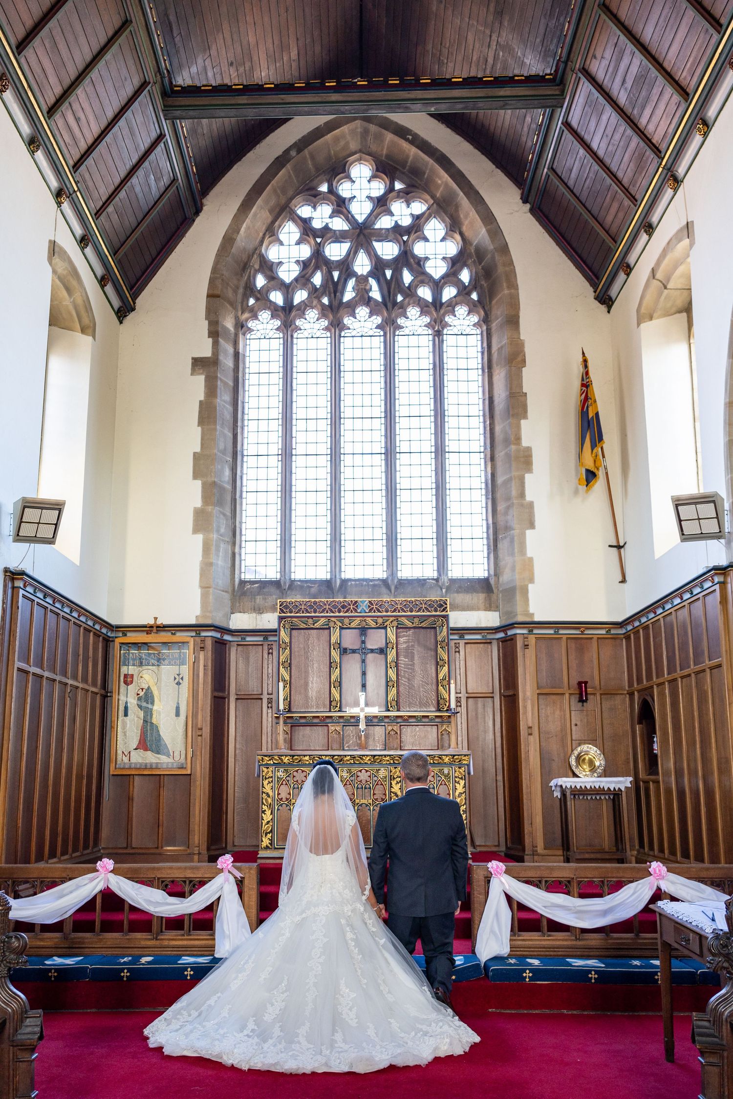 Bride and groom walk to altar in church ceremony, elegant North East UK wedding with stained glass and classic traditional setting
