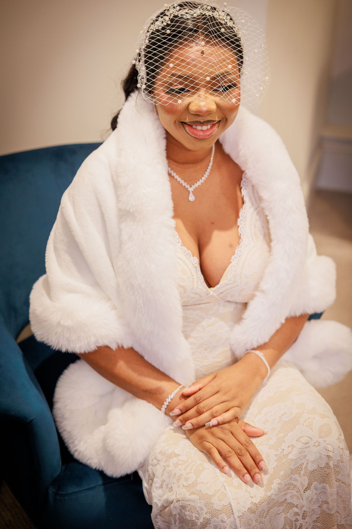 Bride seated at The Story, Durham; elegant veil and wrap, smiling in a calm, intimate moment.