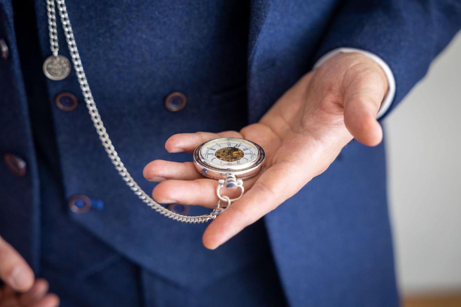 Groom holding vintage pocket watch on chain, elegant wedding detail shot with blue suit, classic timepiece and timeless groom preparation mo