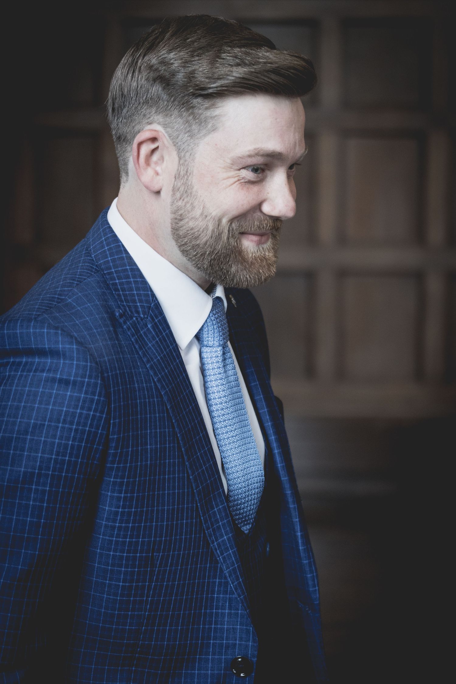 Groom portrait at Preston Park; relaxed smile with classic wood-panelled backdrop.