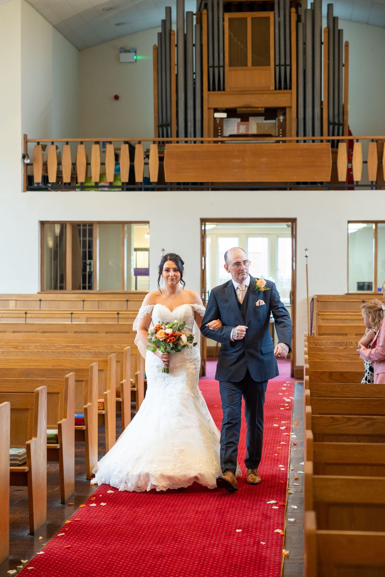 Bride walking down the aisle with her father, a timeless ceremony moment inside a bright, intimate church setting.