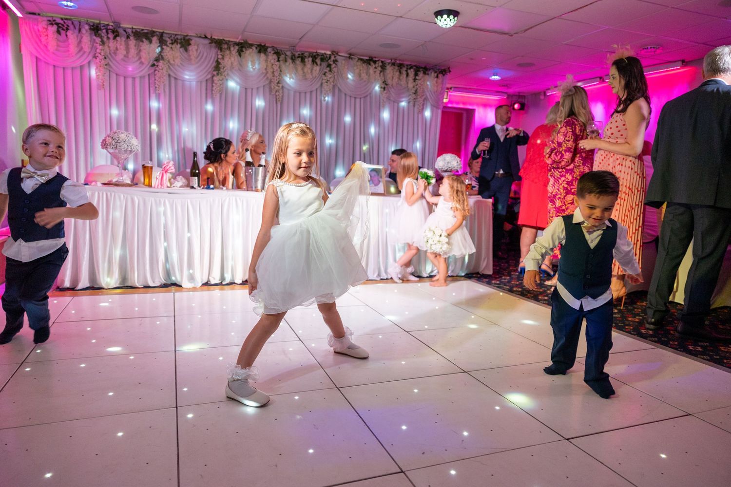 Children dancing at wedding reception, fun kids on dance floor, joyful party atmosphere, colourful lights, lively UK wedding celebration