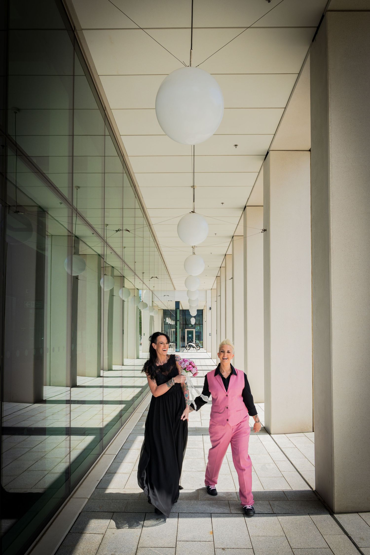 Two brides laughing together at Sunderland City Hall on their wedding day