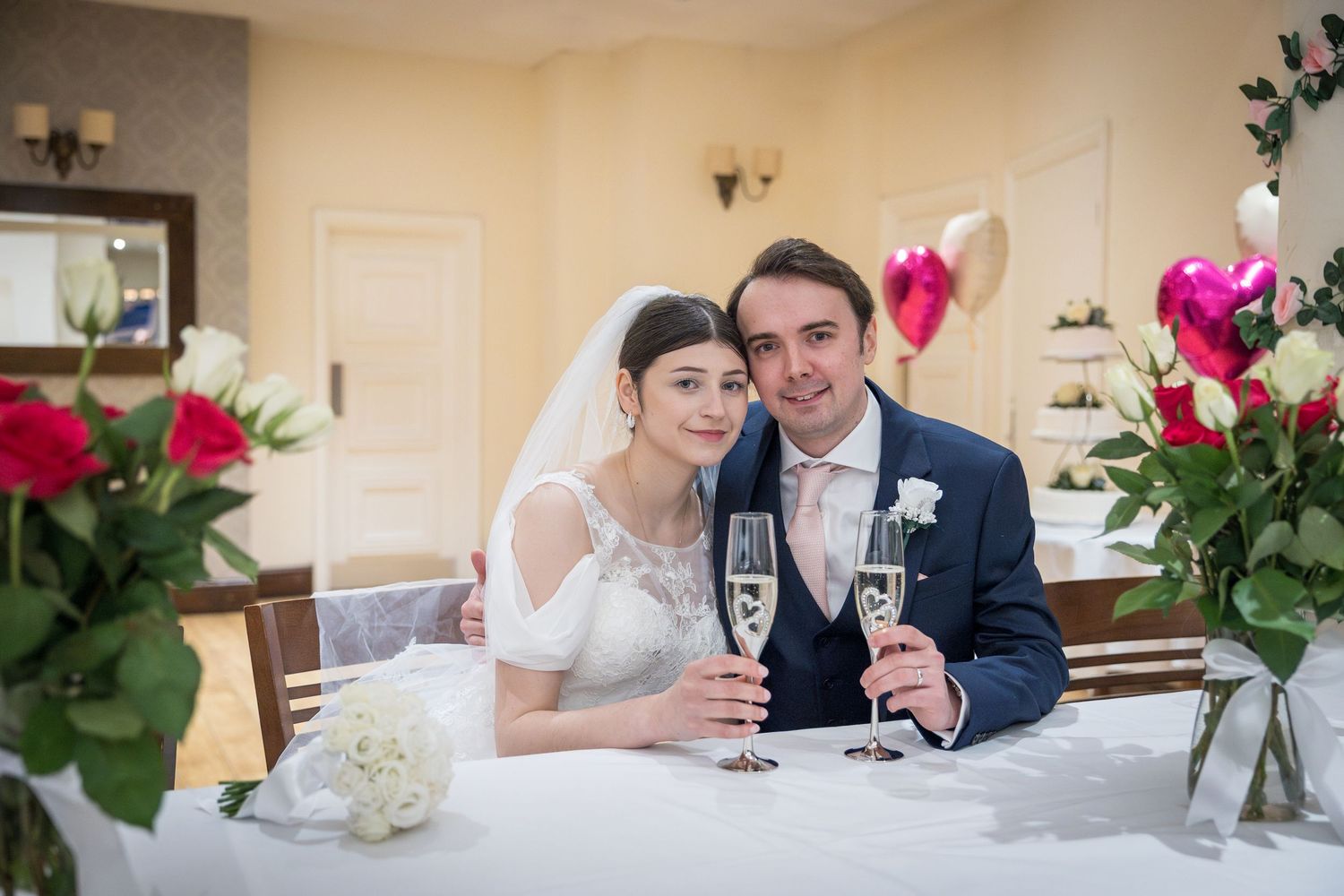 Bride and groom share a toast, holding drinks and smiling; relaxed, intimate wedding moment.