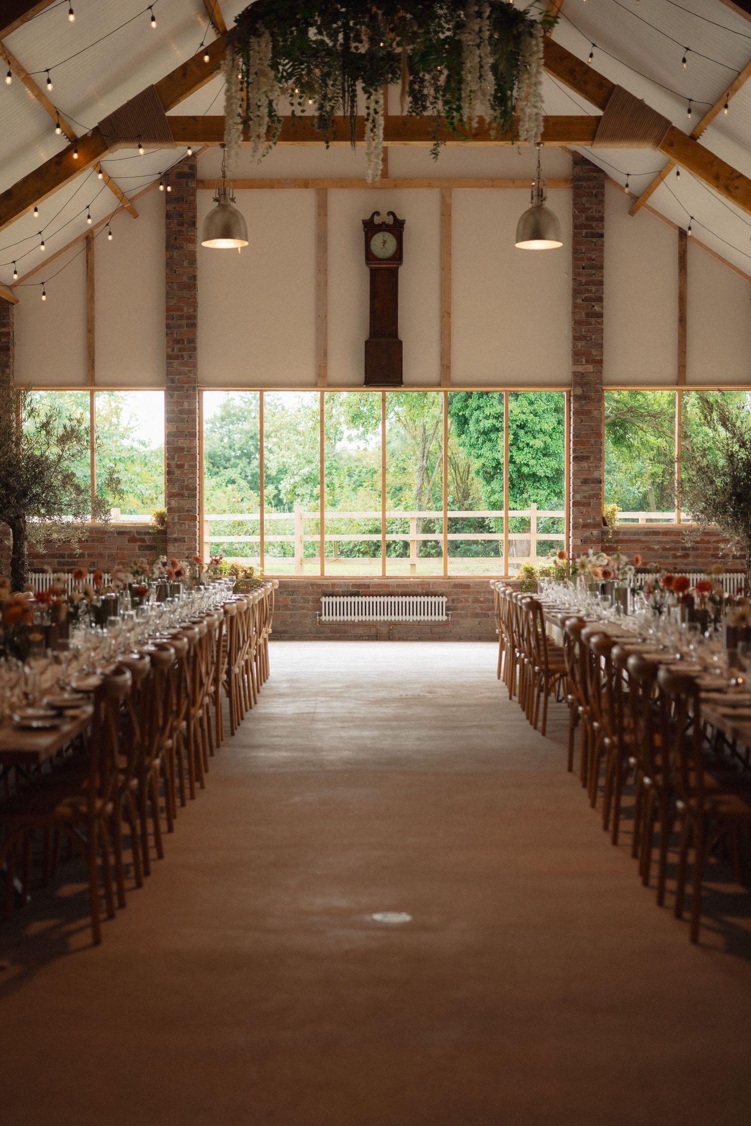 Spacious rustic wedding venue with exposed beams, brick walls and wooden chairs.