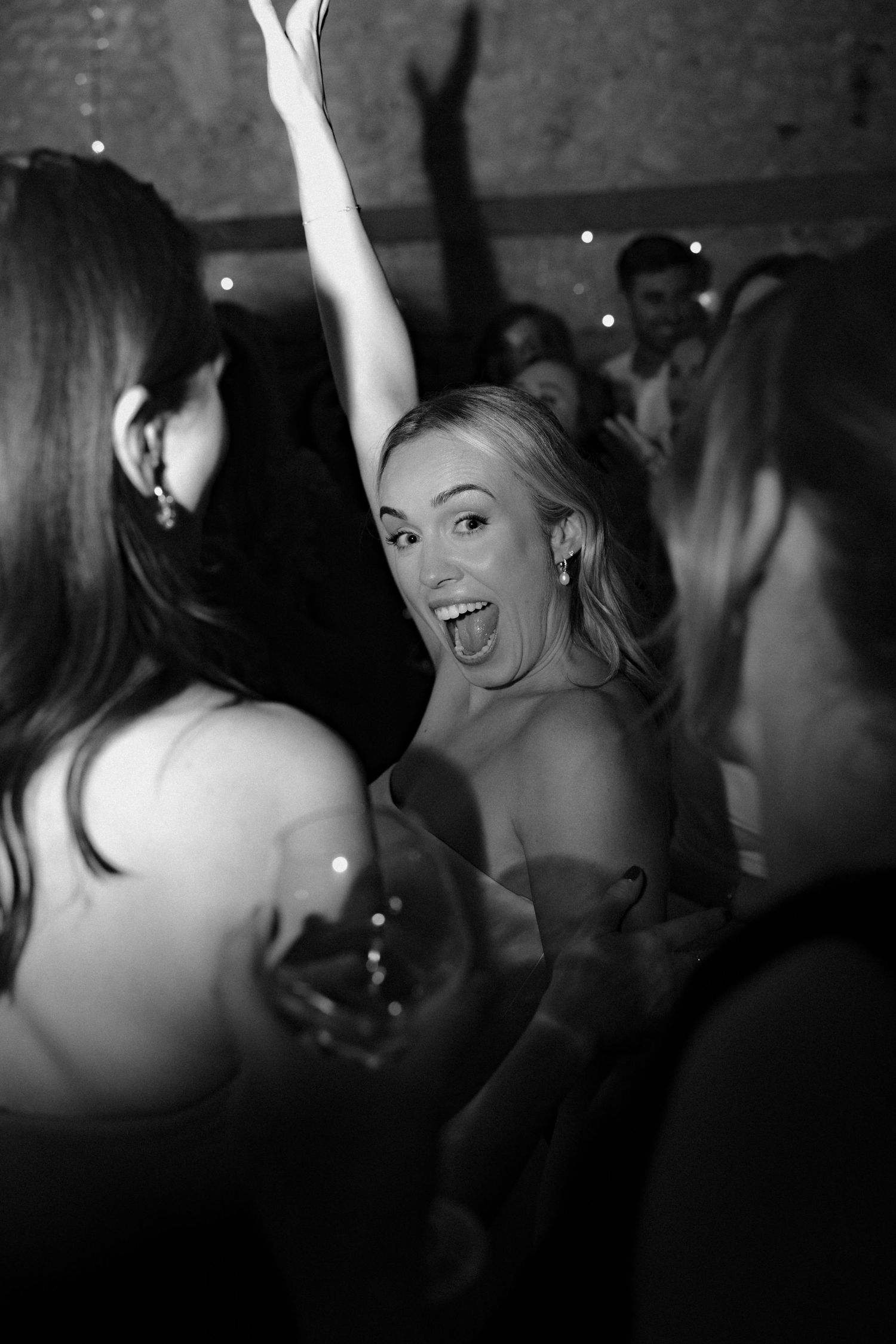 Candid black and white photo of guests dancing at a lively reception party.