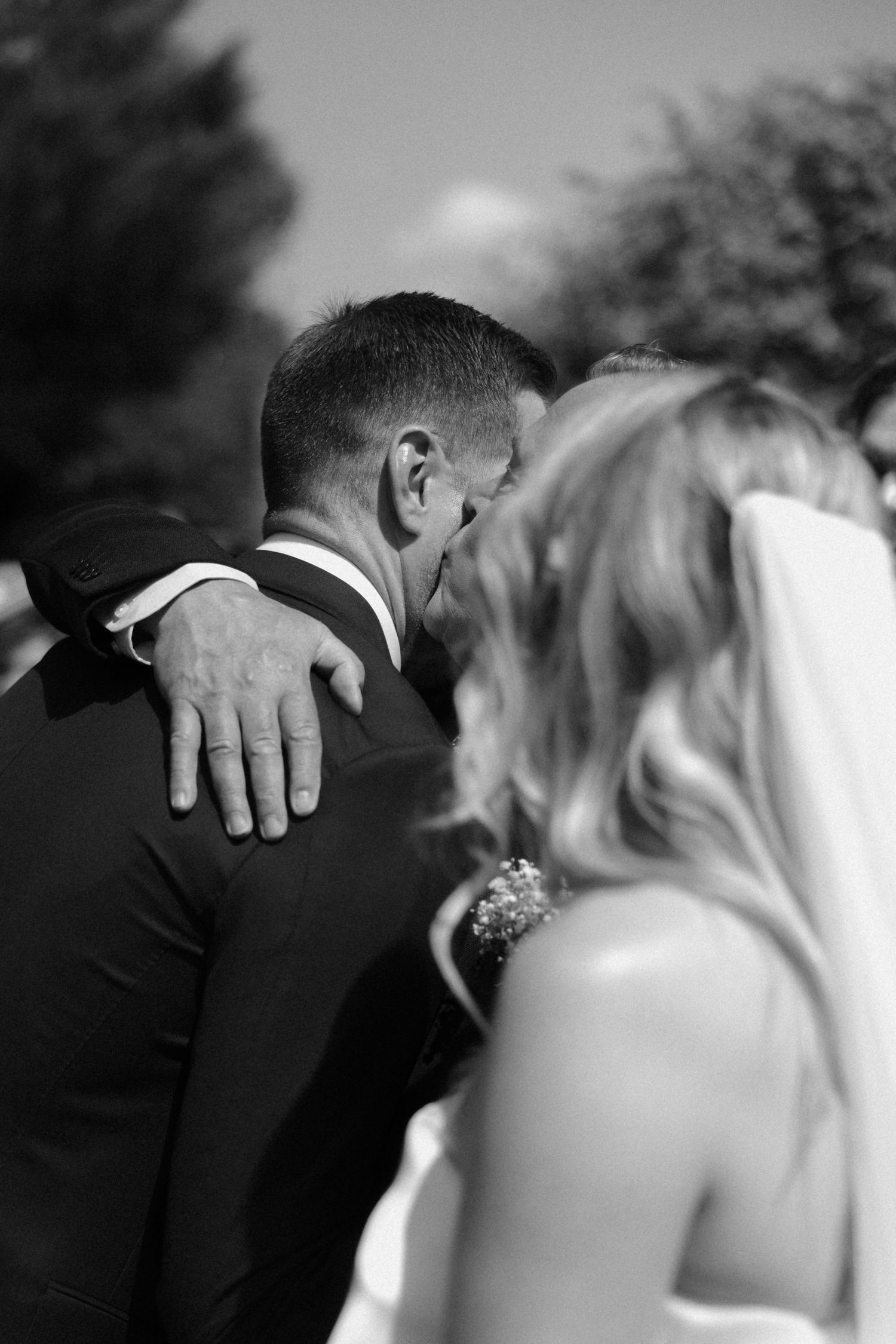 Black and white intimate wedding moment captured during outdoor ceremony.