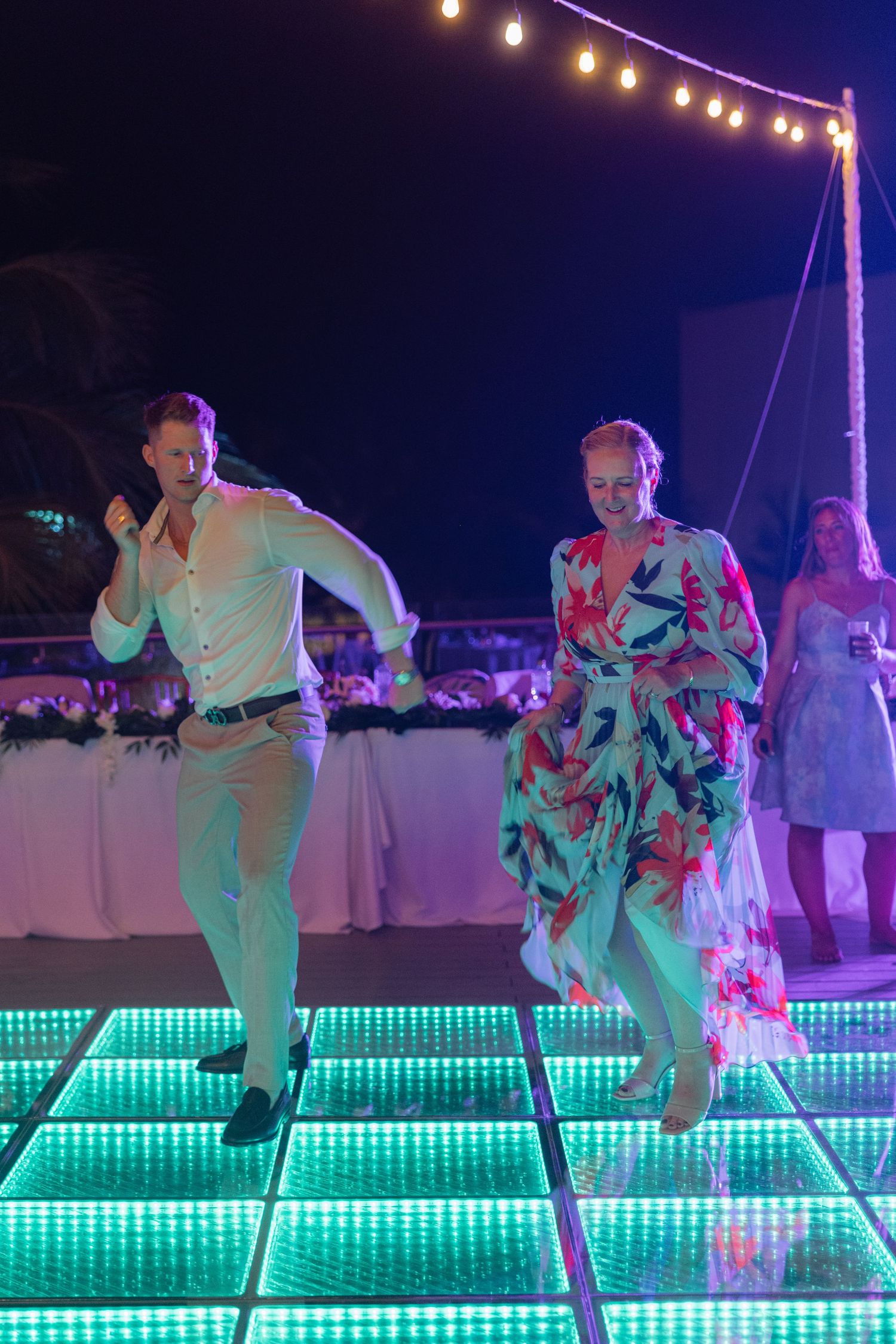 Couple performing choreographed dance moves over a green LED-lit dance floor.