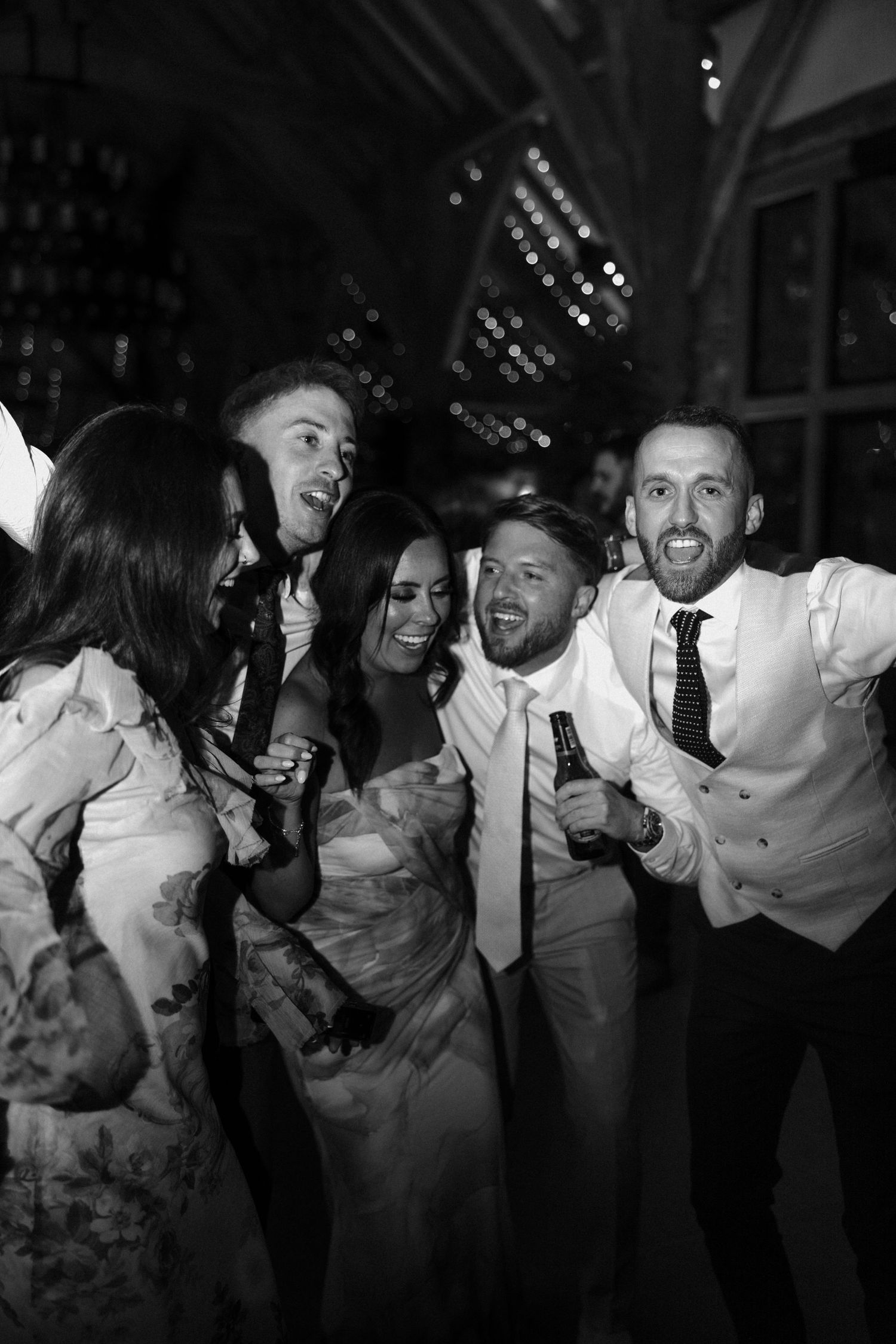 Wedding guests laugh and dance together during a fun reception celebration.