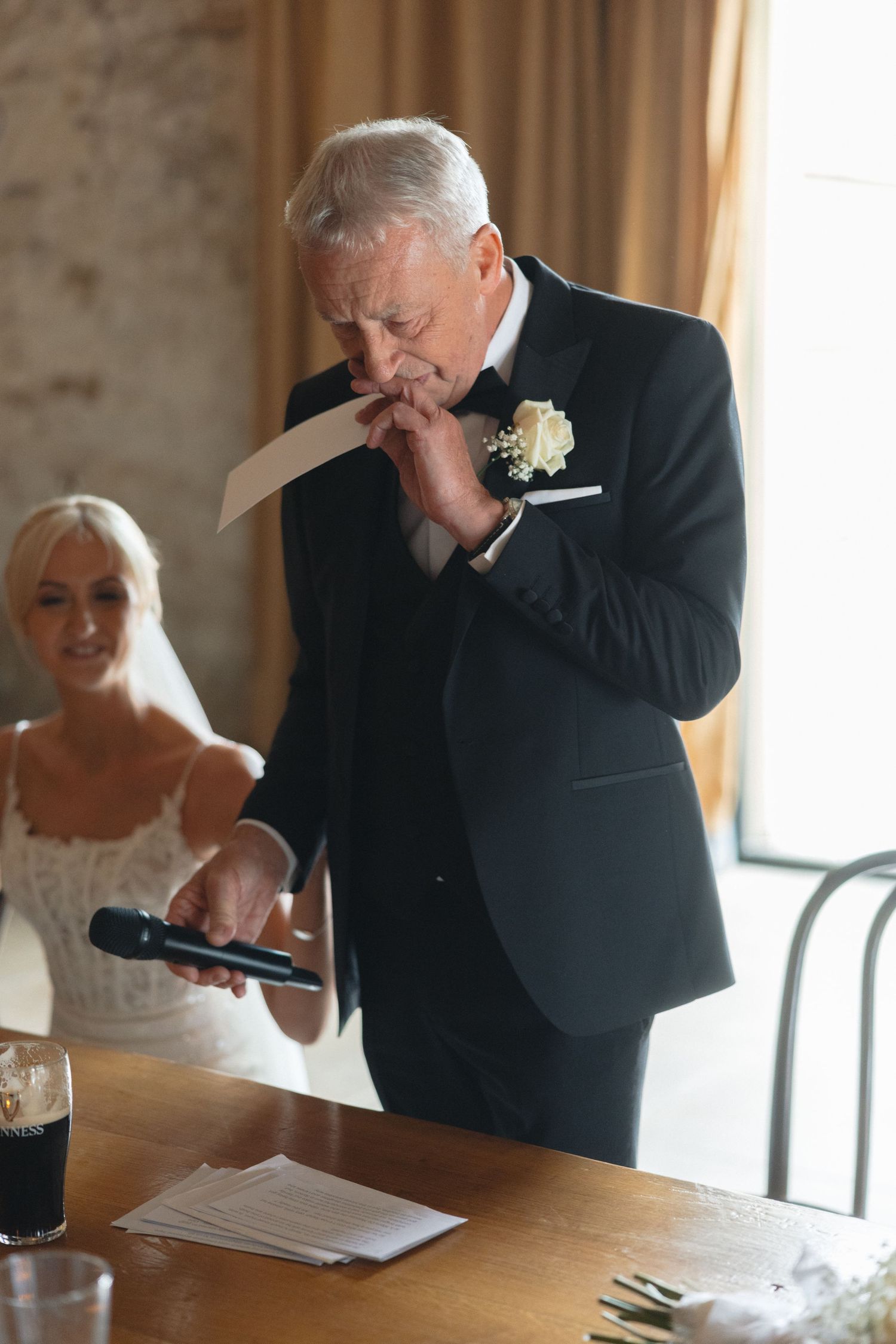 Emotional moment during wedding speeches at an elegant indoor reception.
