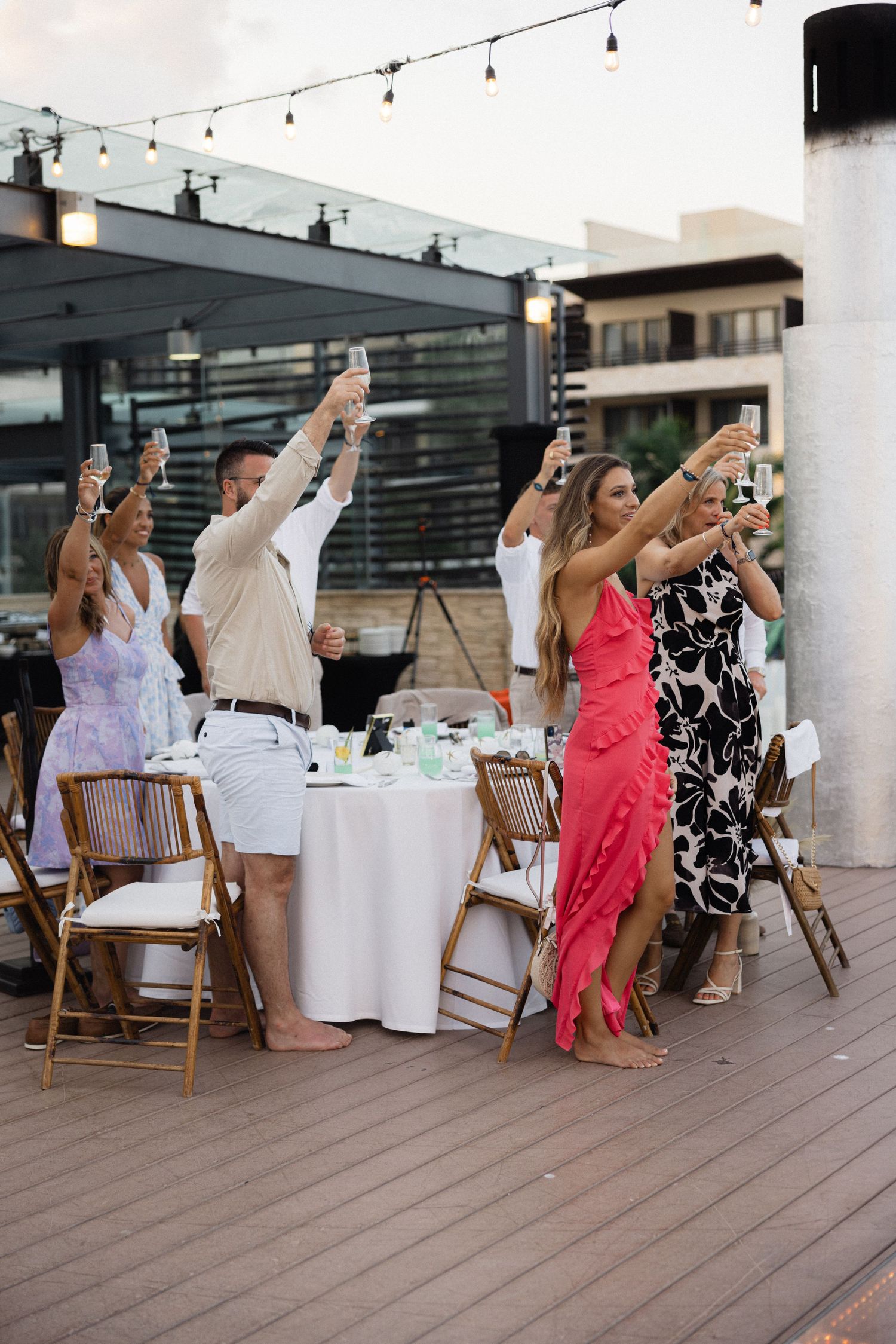 Wedding guests raising their glasses in a toast during an outdoor celebration.