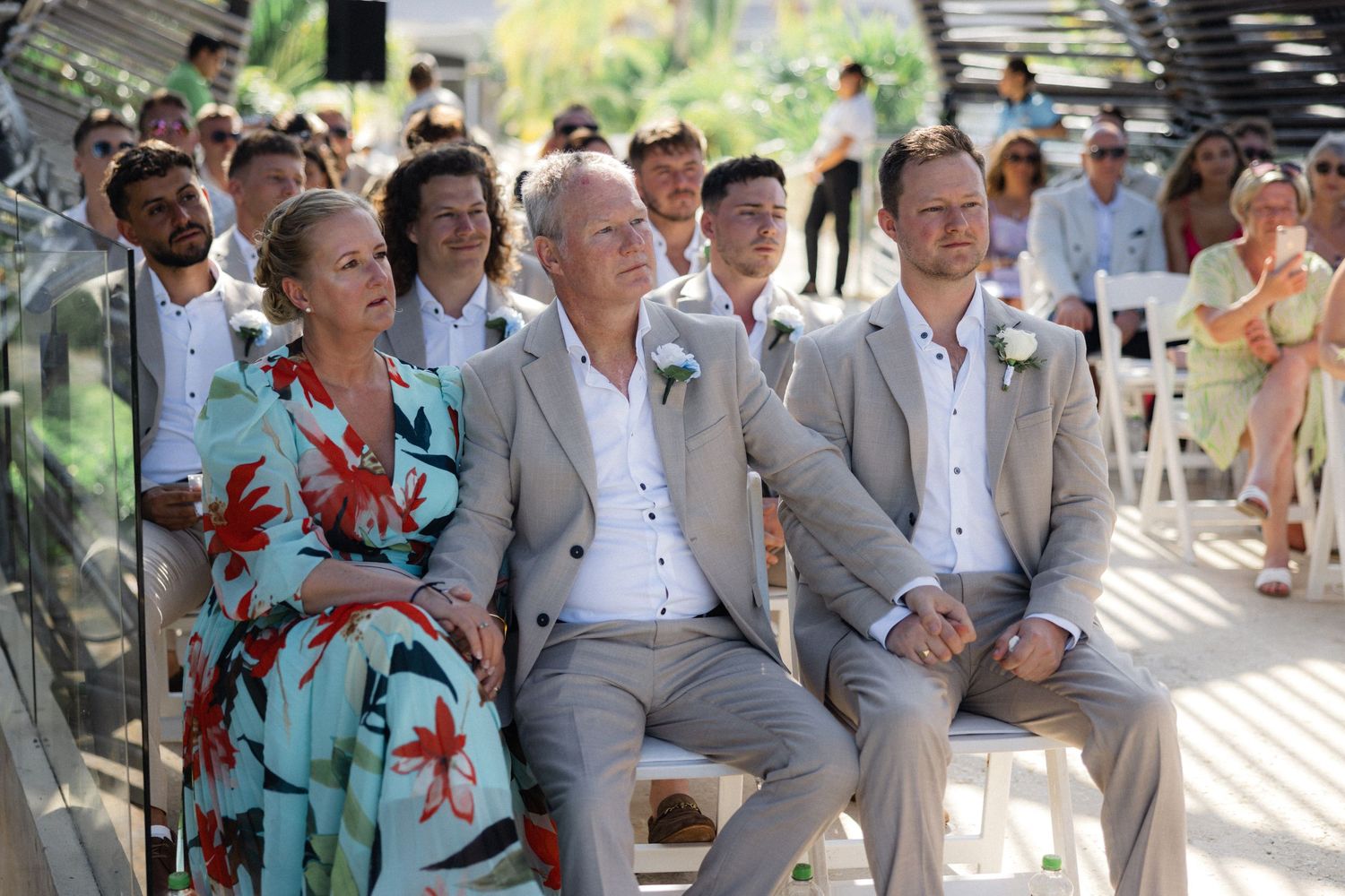 Wedding guests seated in rows under pergola with dramatic lighting effects.