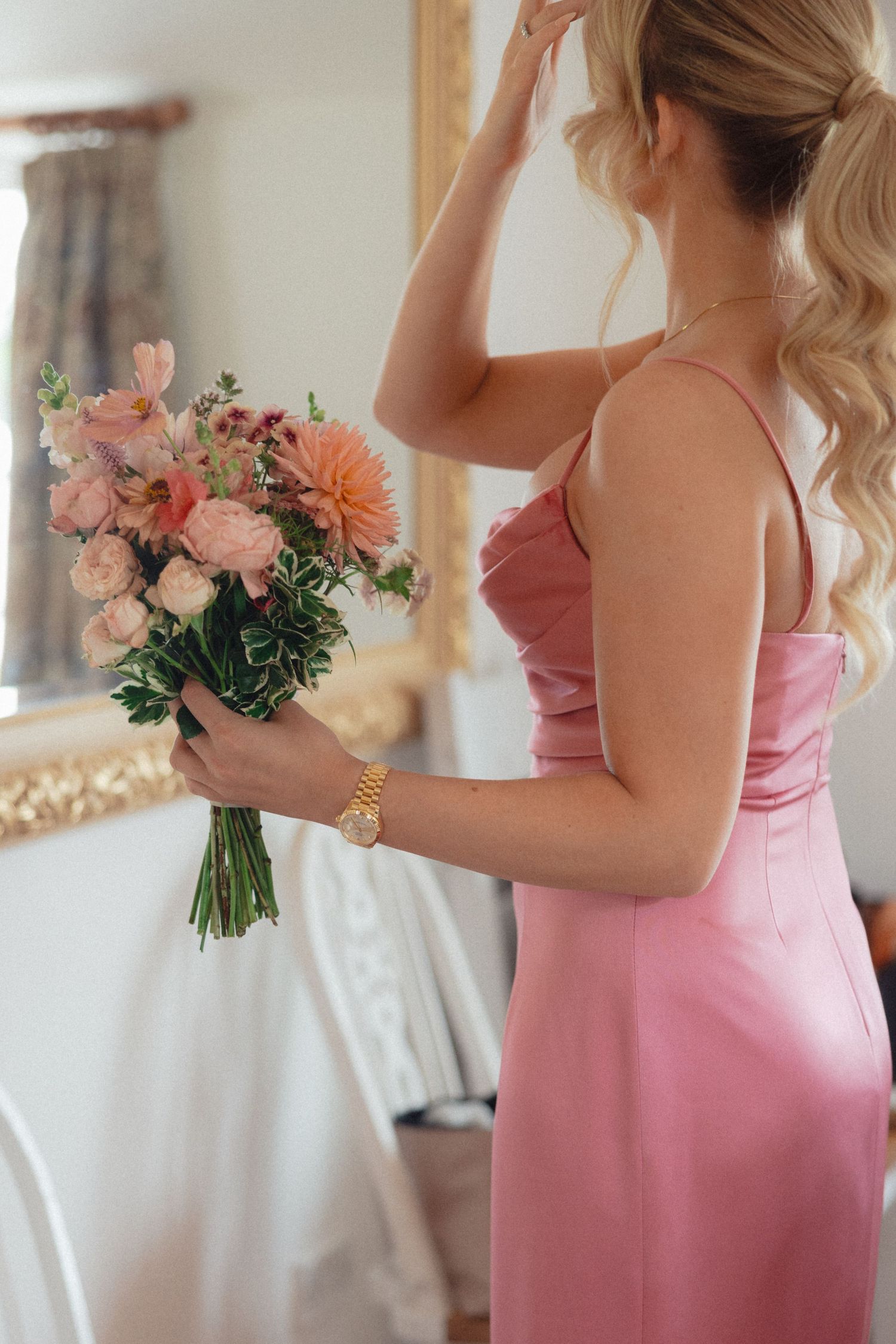 Bridesmaids in pink dresses holding coral and peach floral bouquets.