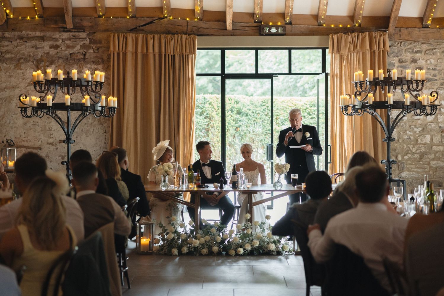 Wide view of wedding reception venue with stone walls and elegant lighting.