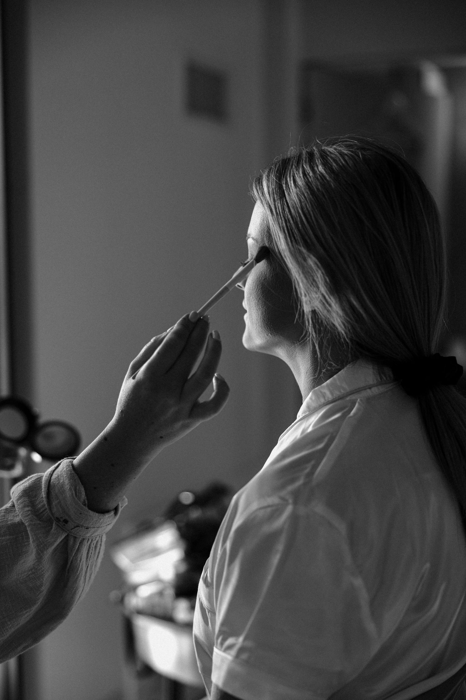 Black and white series showing makeup application in profile view with soft lighting.