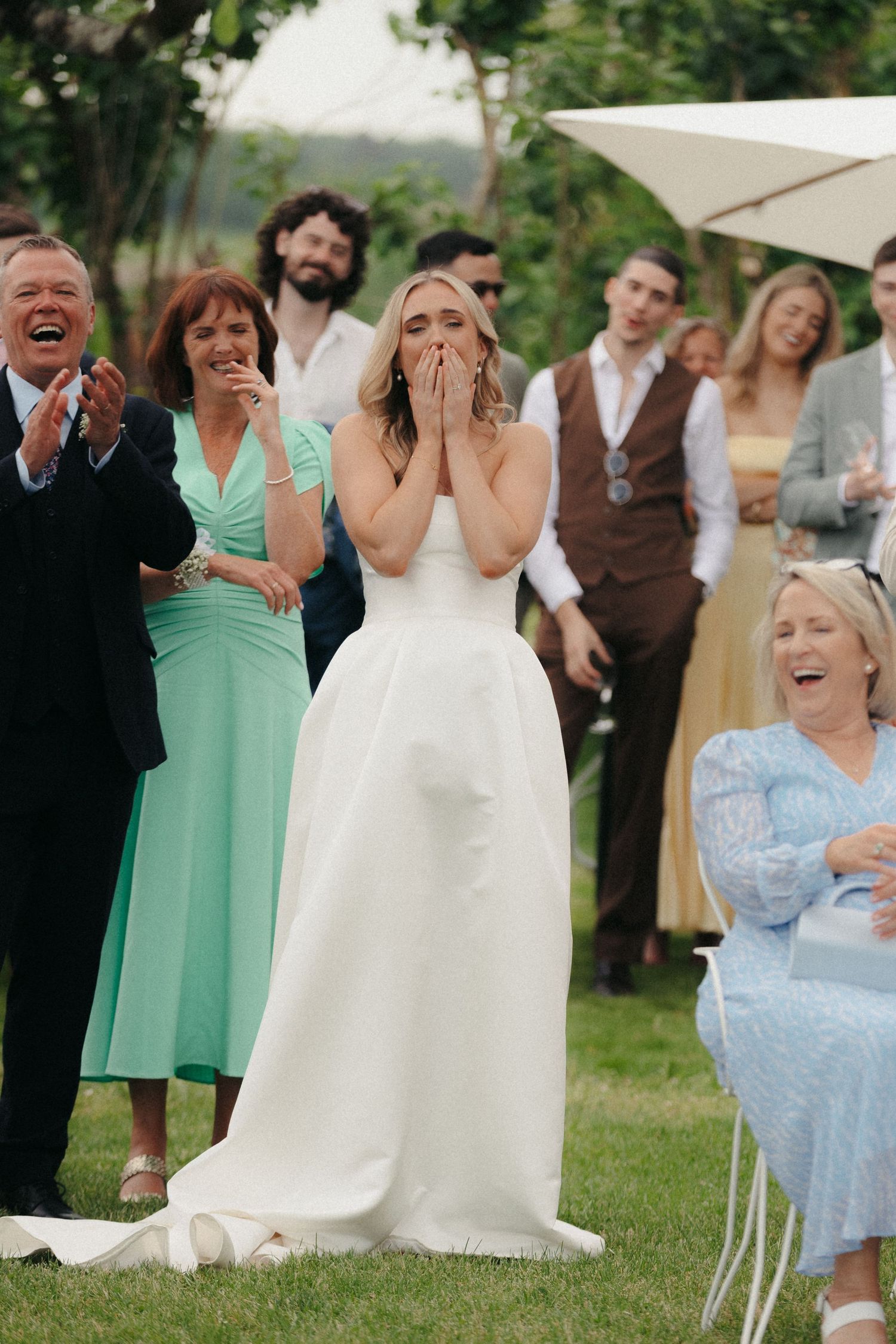 Emotional reactions from wedding attendees during an outdoor ceremony with mint and white decor.