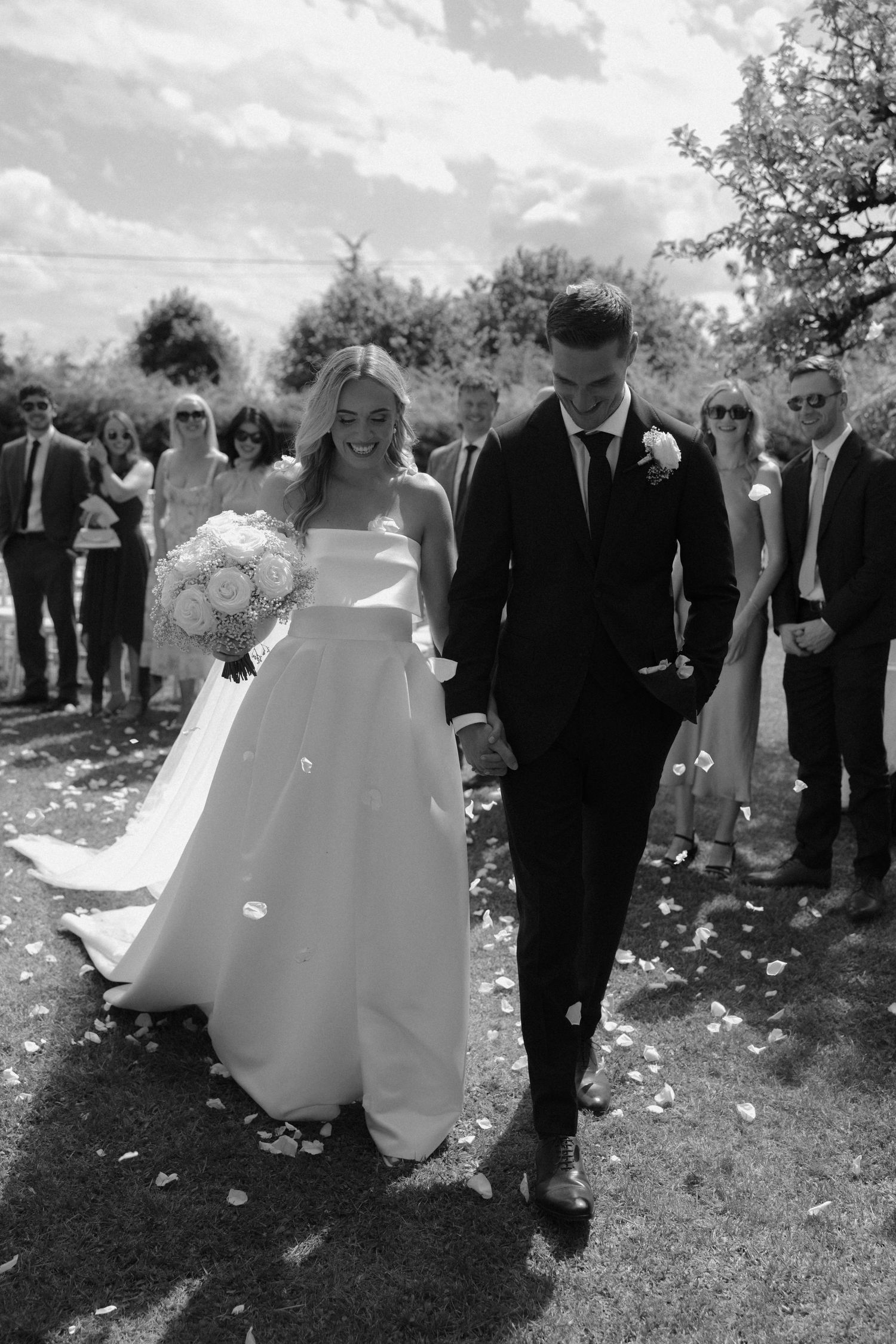 Wedding celebration with flower petals being tossed in a garden setting.