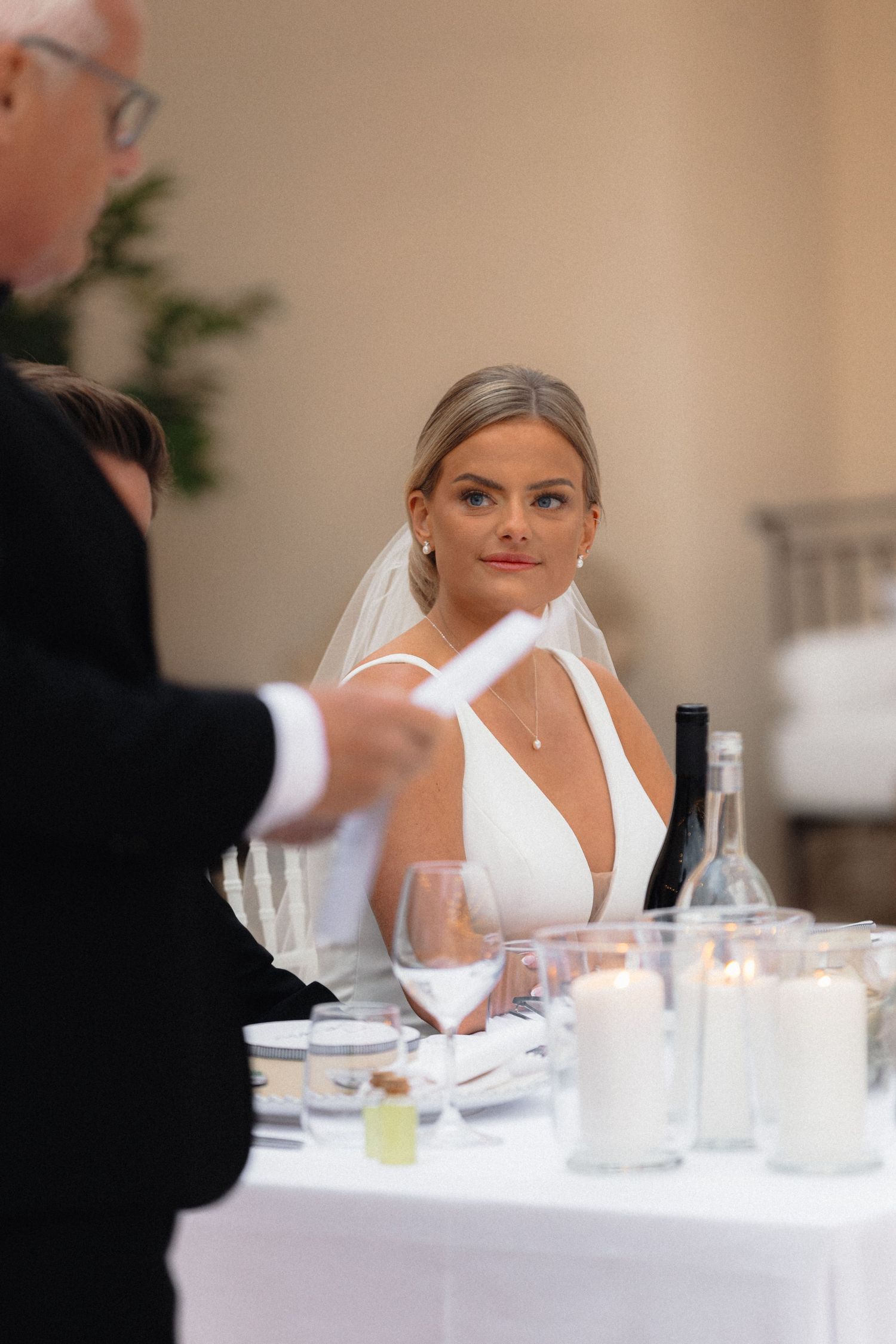 Elegant wedding reception table setting with white linens and glassware.