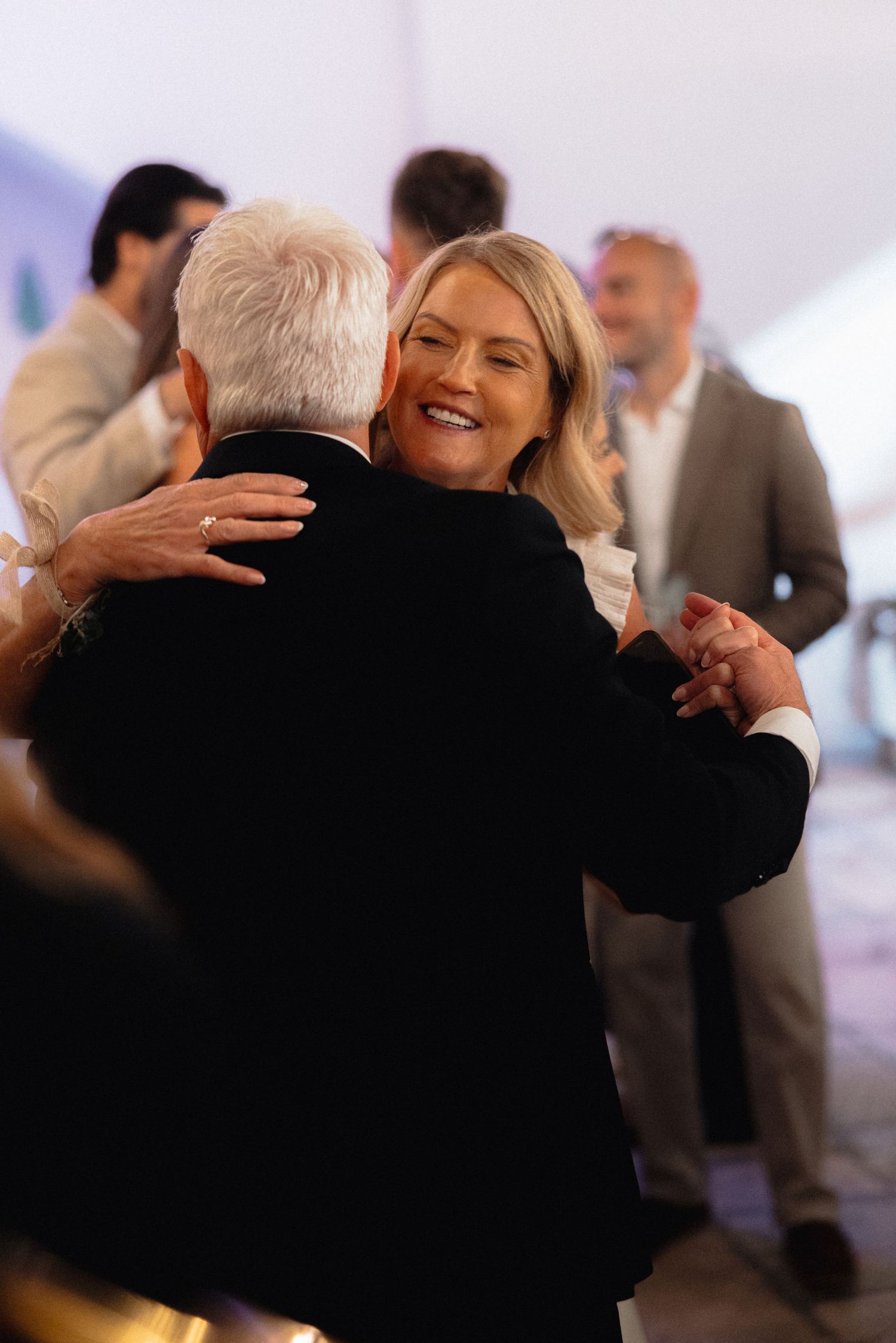 Emotional embrace between wedding guests during reception celebration.