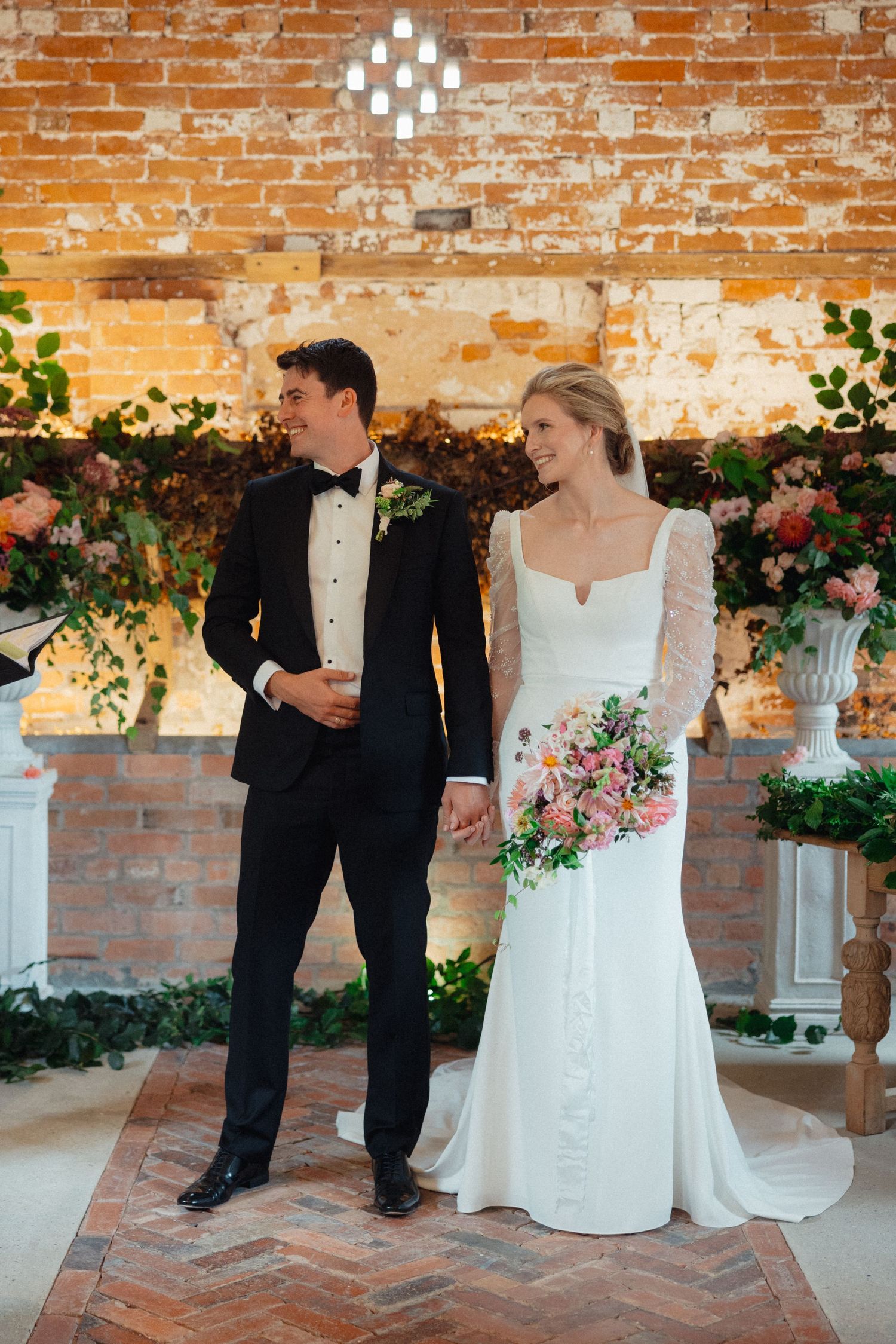 Wedding celebration in an exposed brick venue with elegant floral arrangements and lighting.