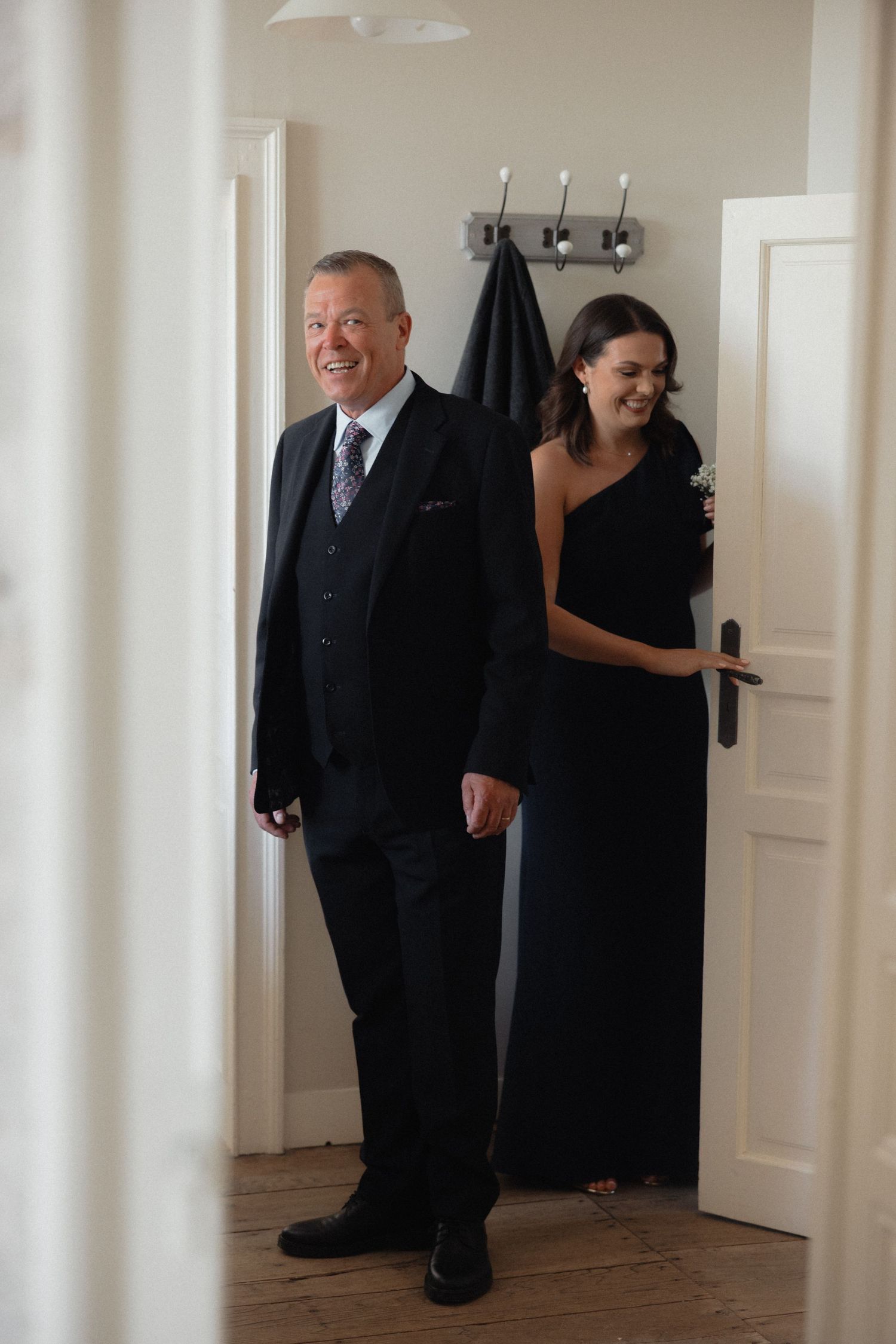 Man in dark suit standing in a bright hallway before a wedding ceremony.