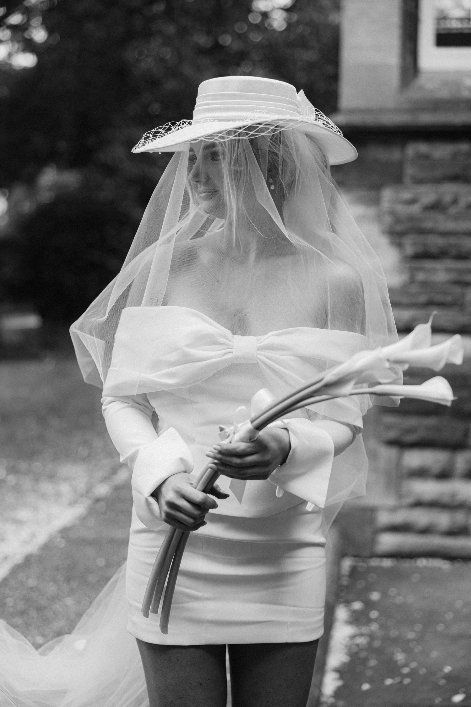 A vintage-style bridal portrait featuring a white hat and flowing veil.