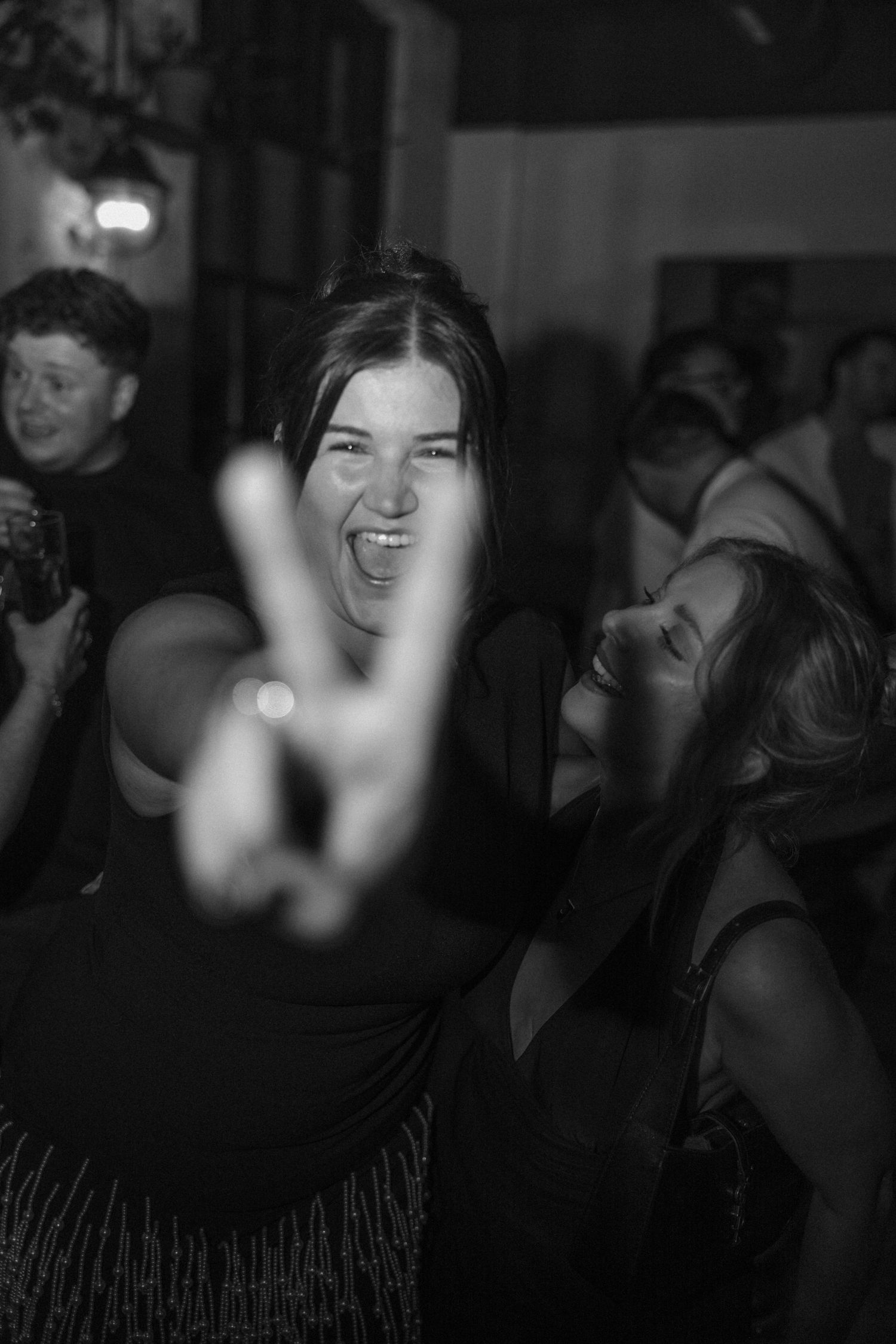 A black and white party photo showing joyful celebration with a peace sign gesture.