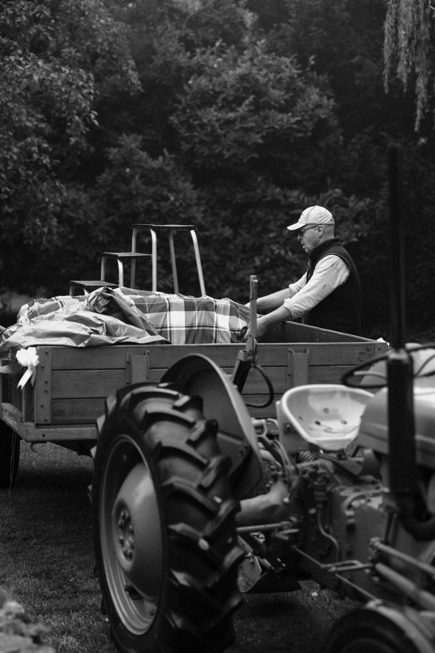 Black and white photo of person driving vintage tractor with cargo.
