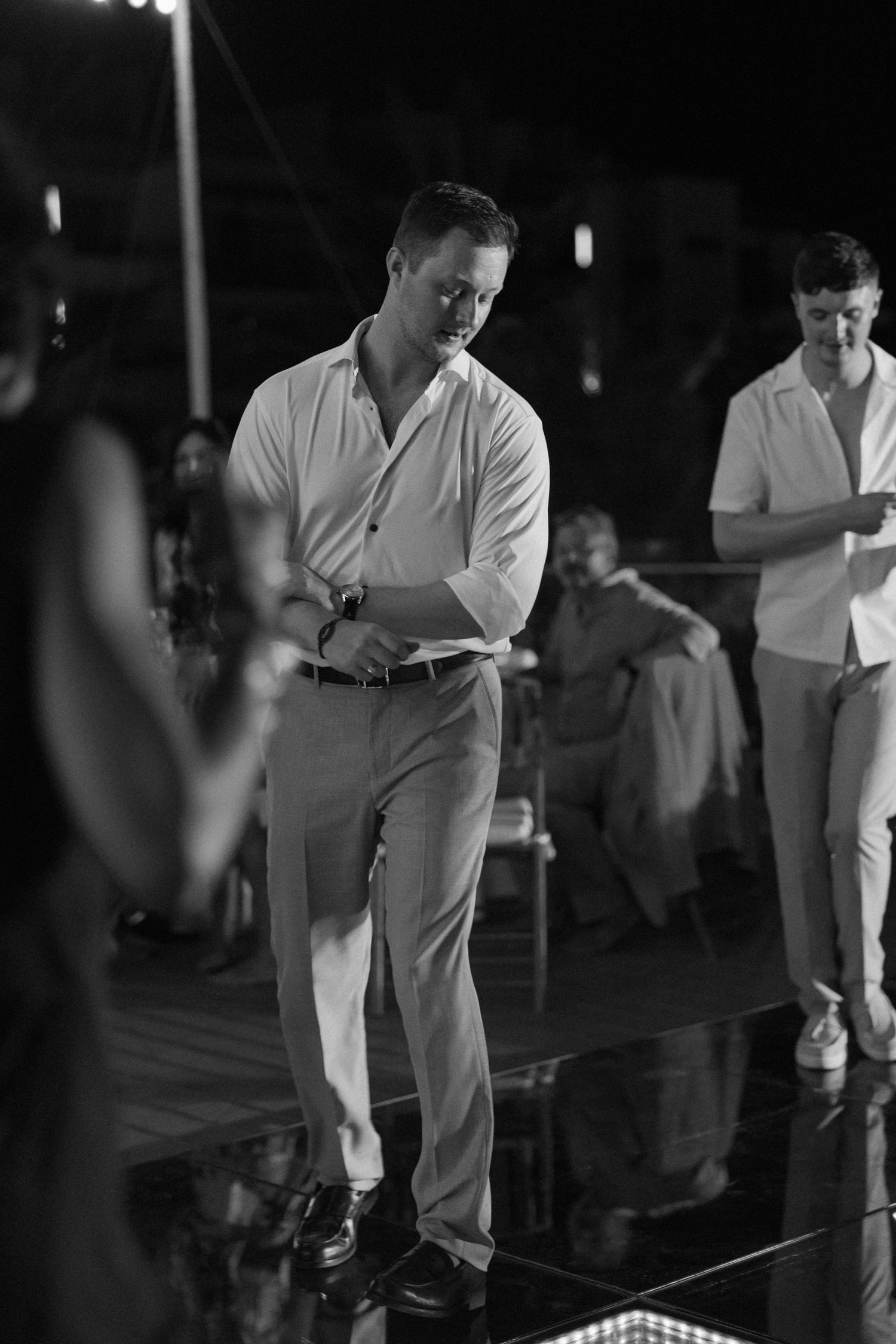 Wedding guests dancing on a reflective light-up dance floor at an evening reception.
