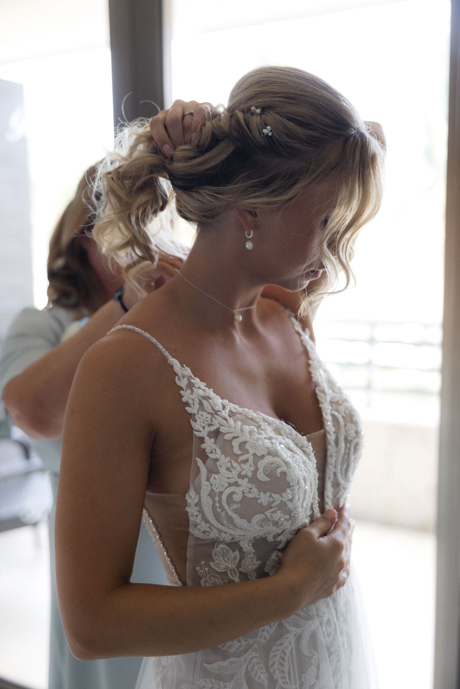 Close-up details of an intricate white lace wedding dress with delicate straps.