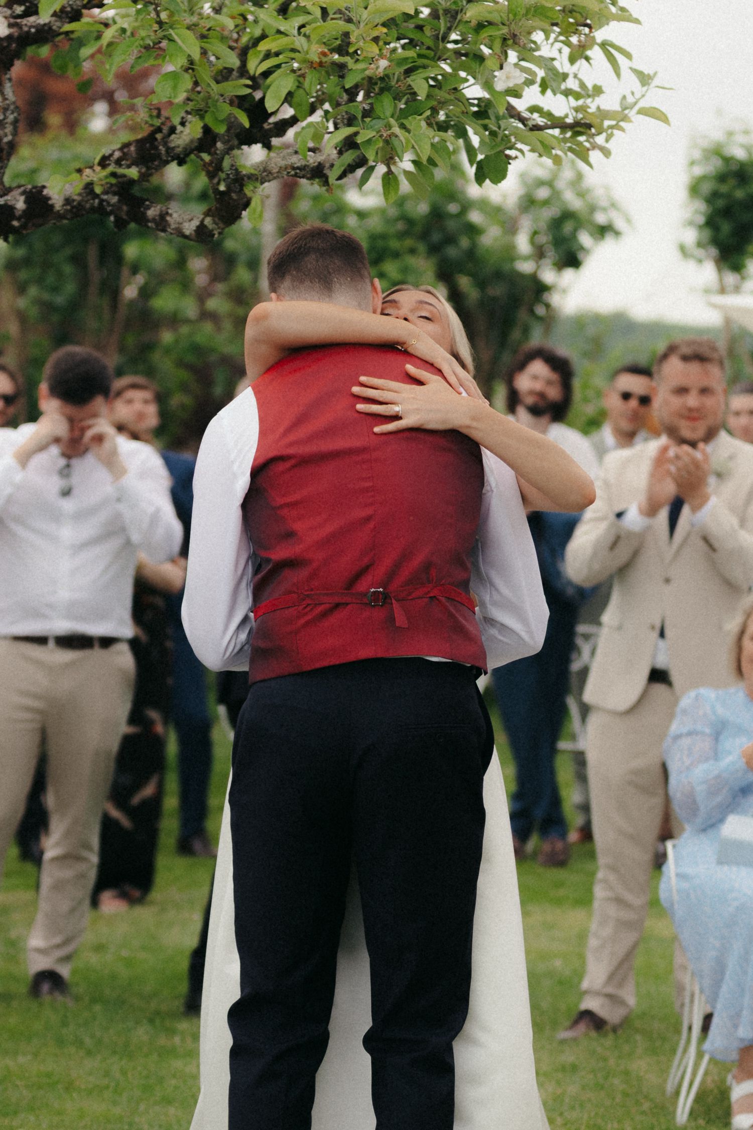 Wedding celebration candid moment with guests in formal attire on a lawn.