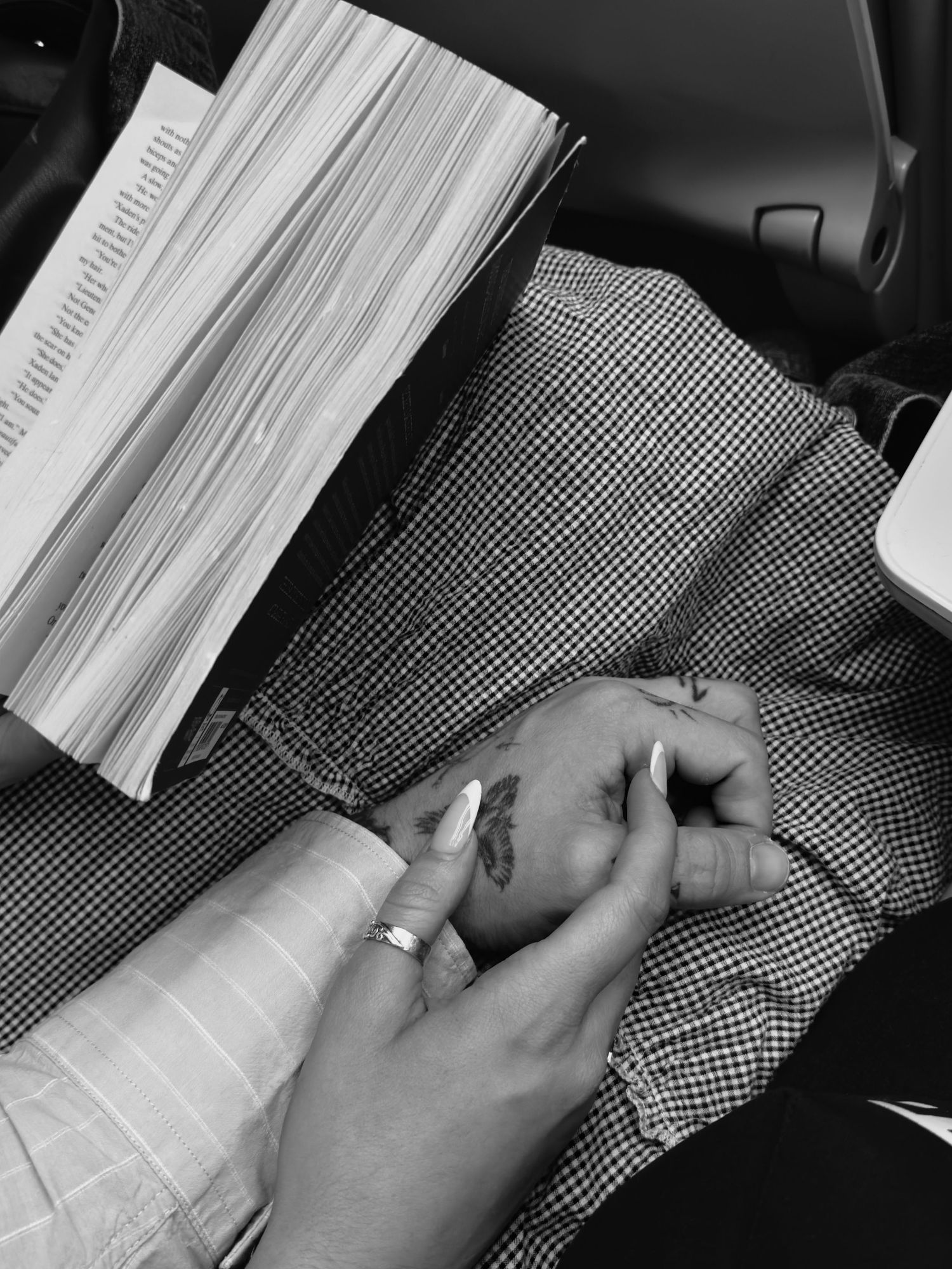 Close-up of hands holding an open book against a checkered fabric background.