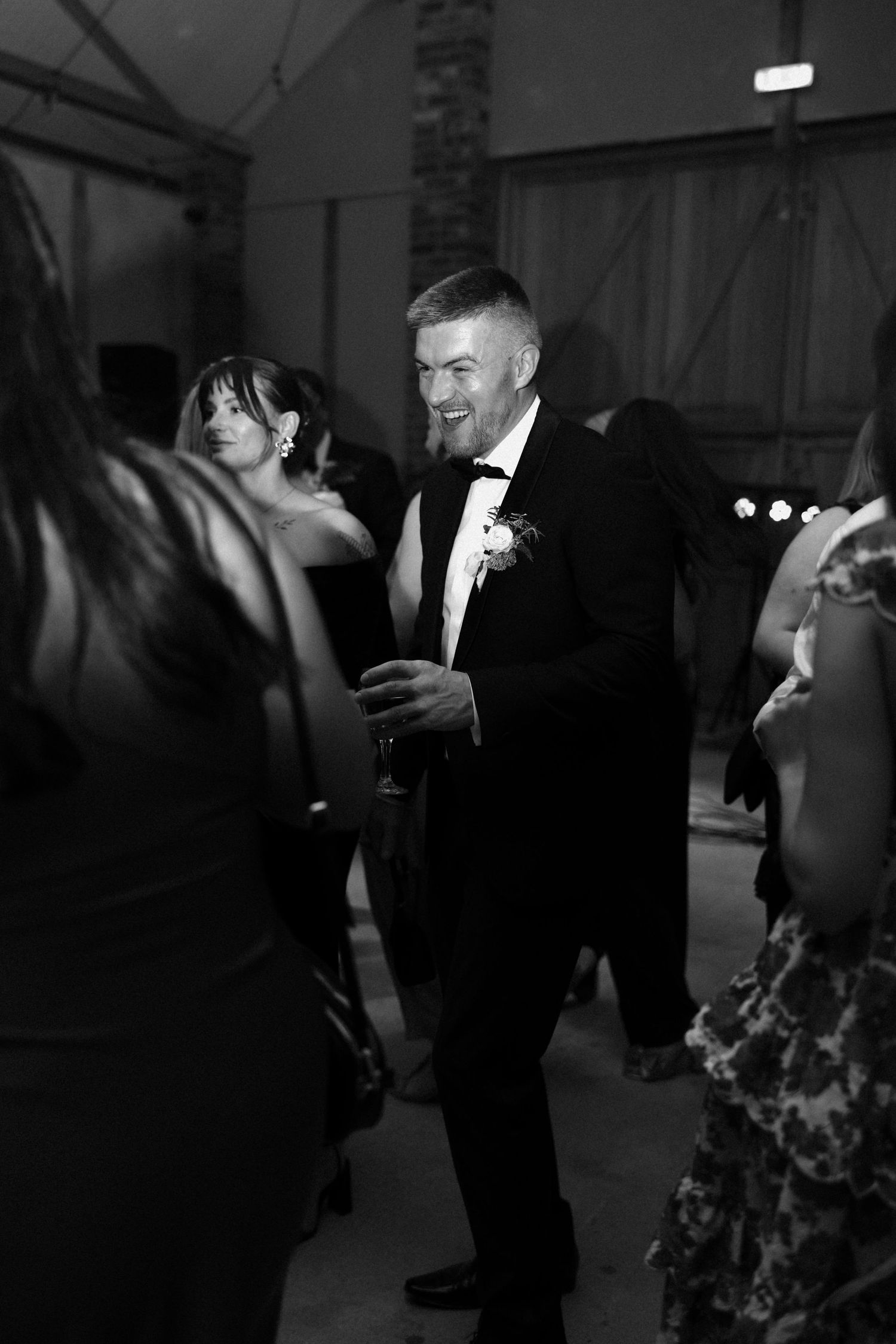Wedding guests dance and celebrate at a dimly lit indoor reception venue.