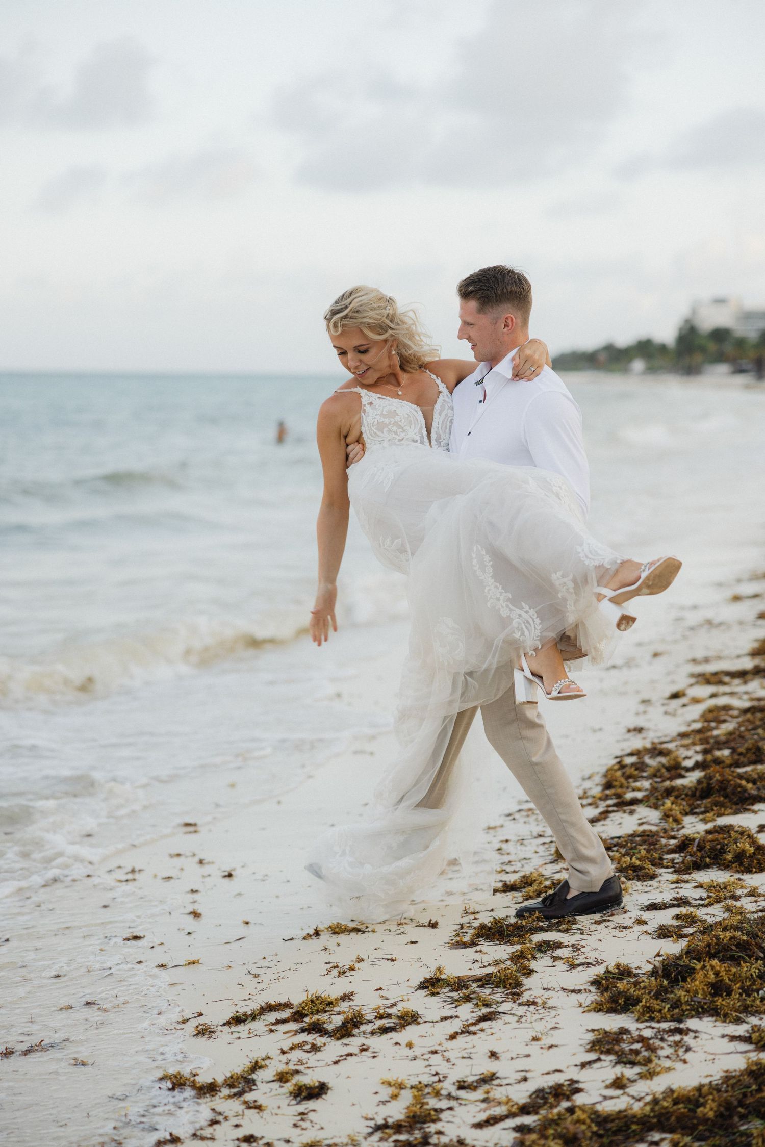 Playful beach wedding photos showing movement and joy as couple dances by the ocean.