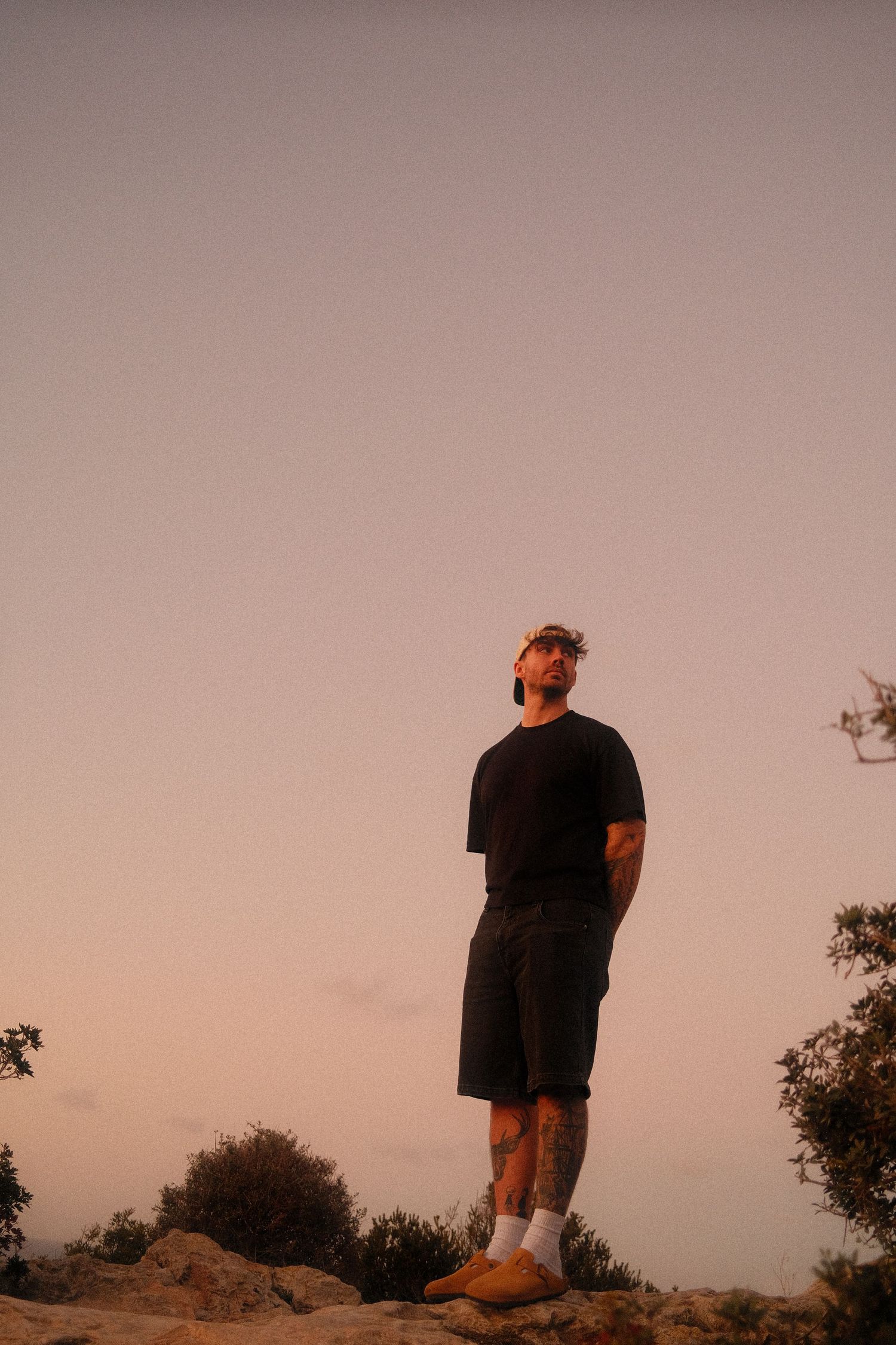 A silhouette of a person standing on a hill during golden hour sunset.