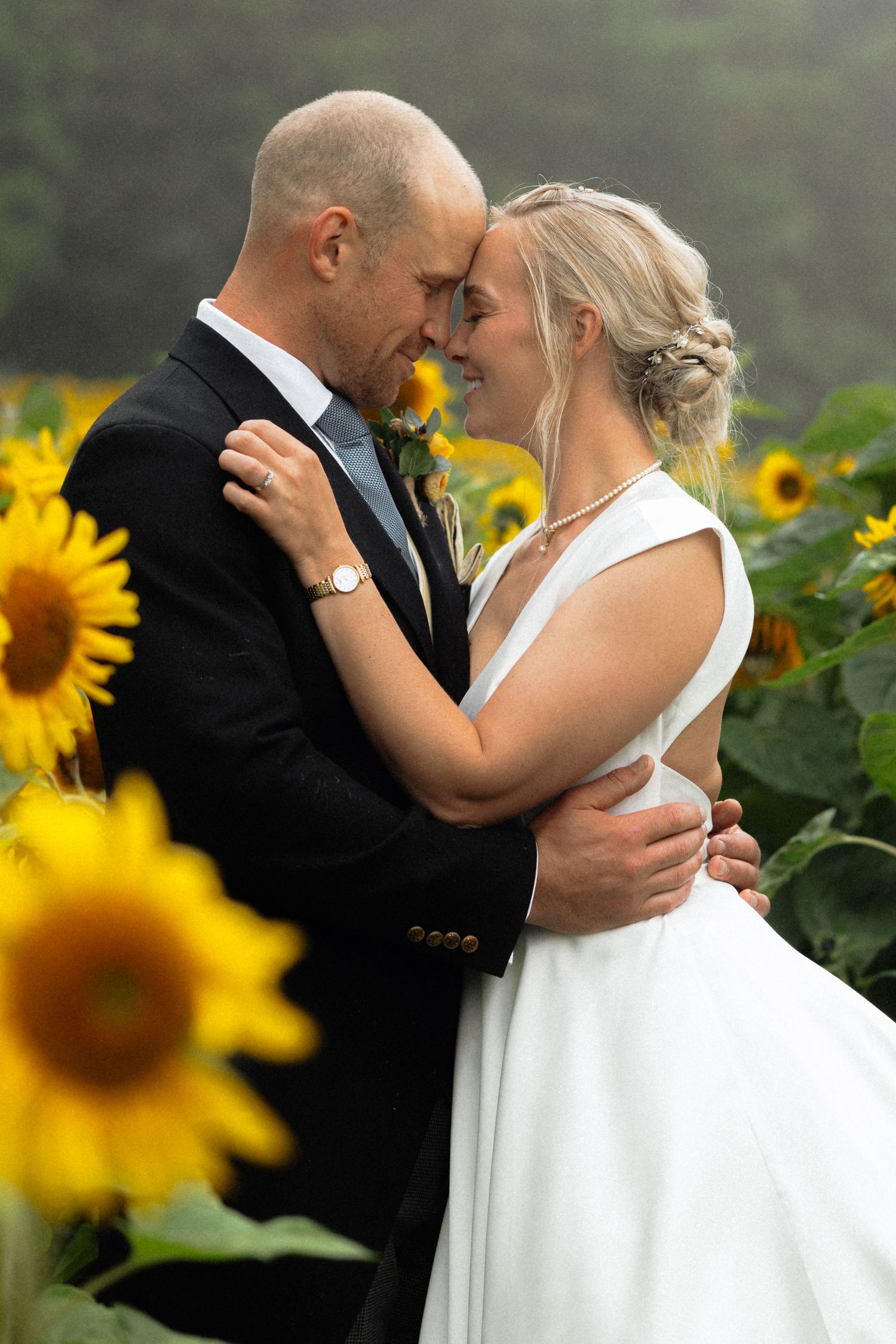 Tender wedding moment photographed in beautiful sunflower field during summer celebration.