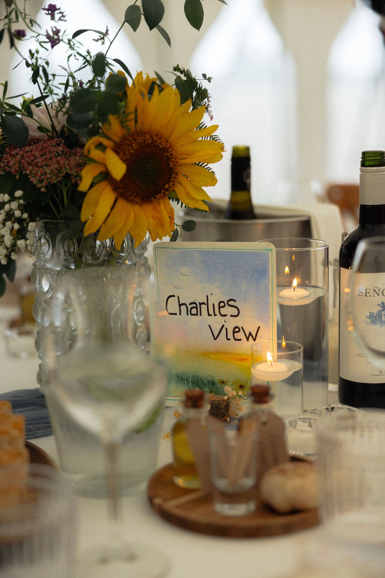 Wedding reception table detail showing place cards, glassware and sunflower decorations.