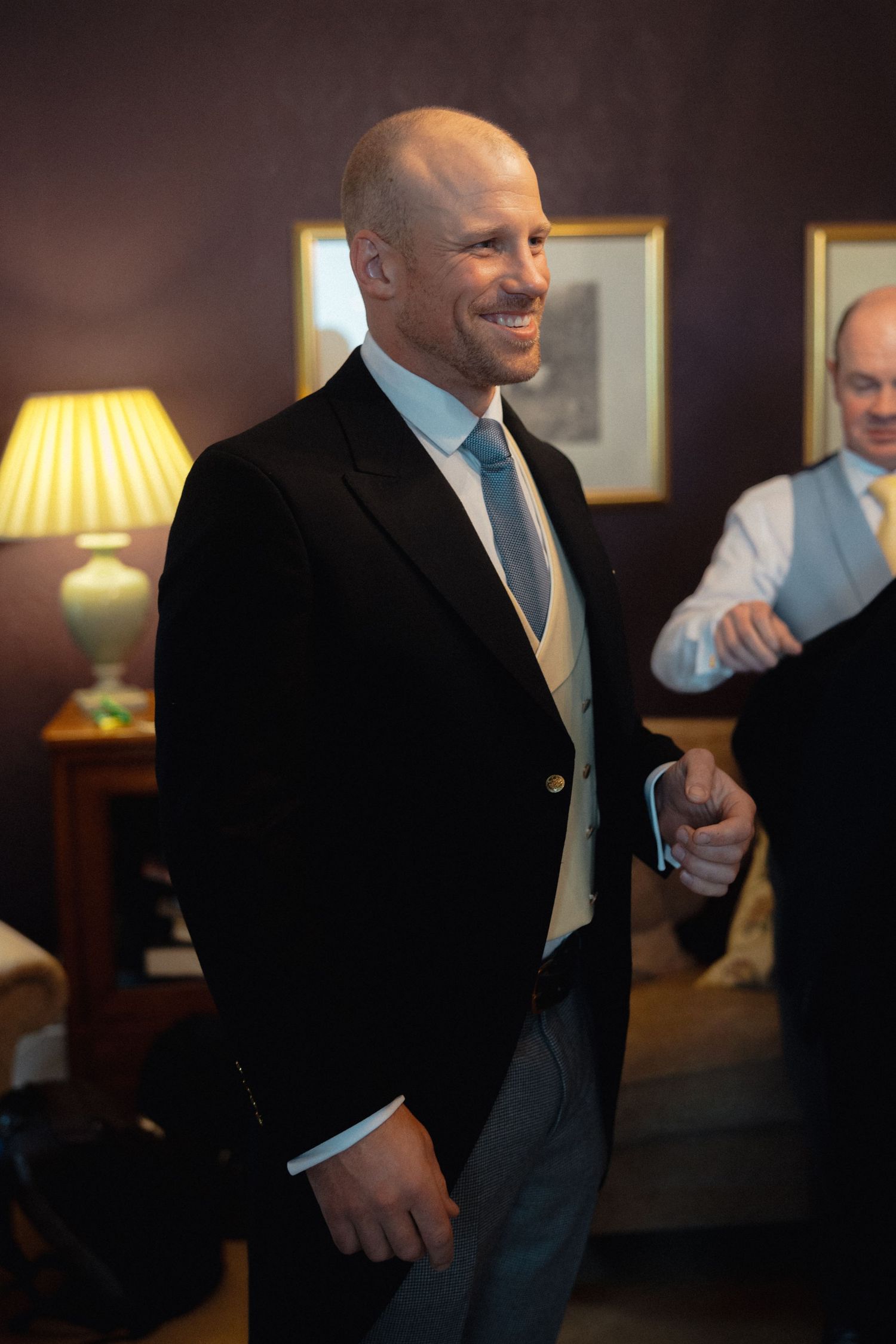 Two people in formal attire sharing a lighthearted moment in a dimly lit room.