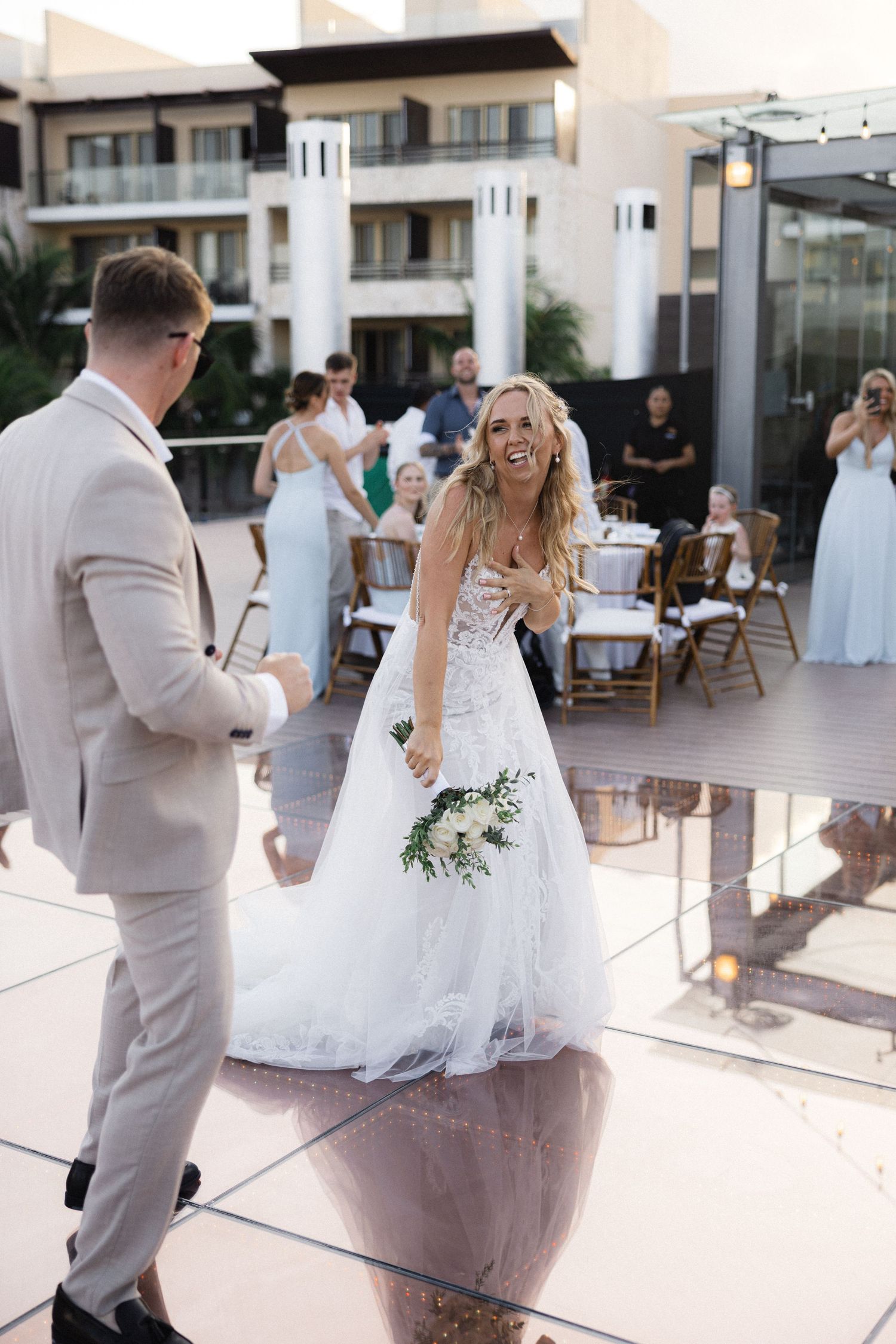 Joyful wedding dance sequence with white dress twirling at resort venue.