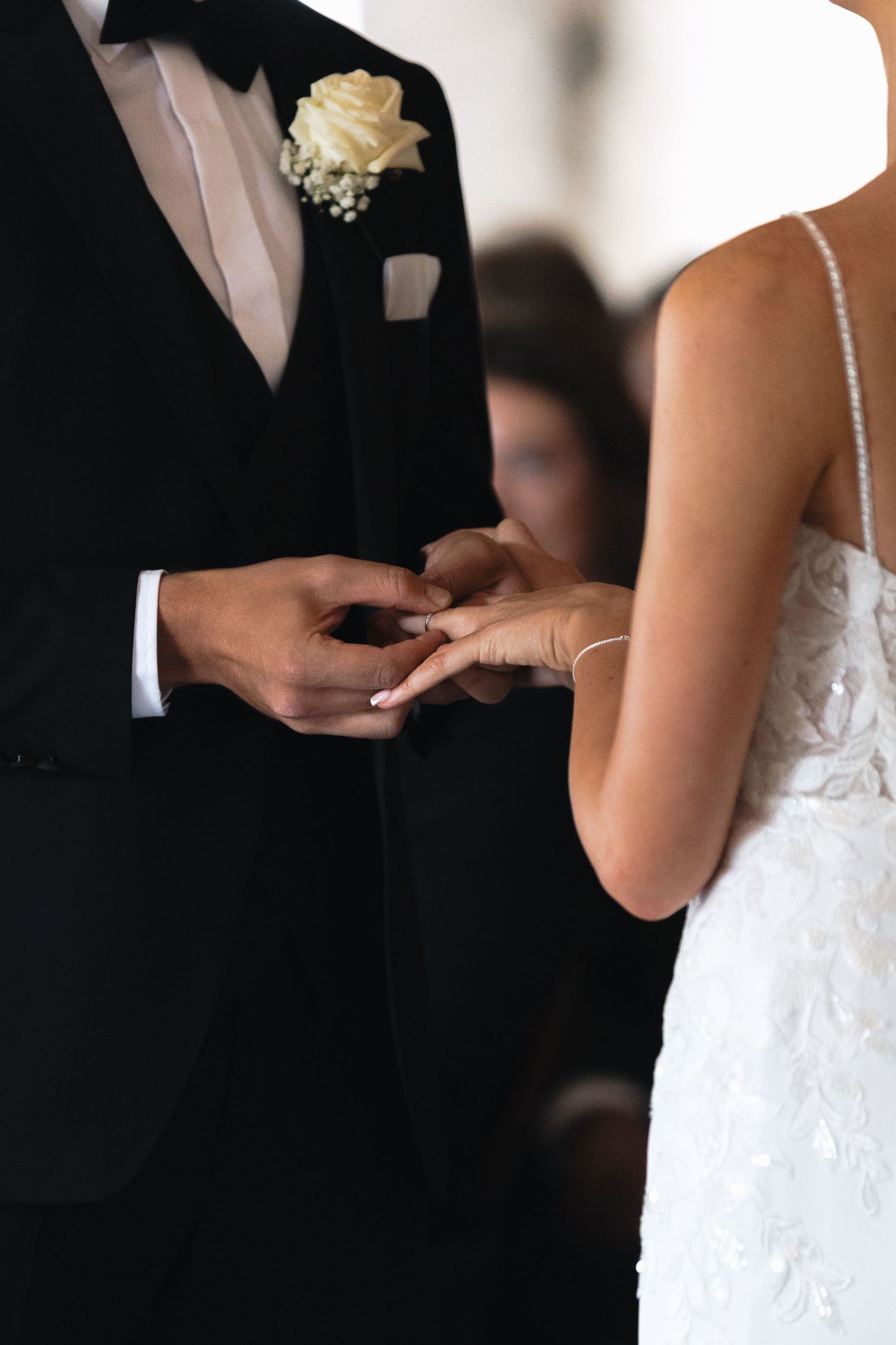 Close-up shots of wedding ring exchange during ceremony in black and white.