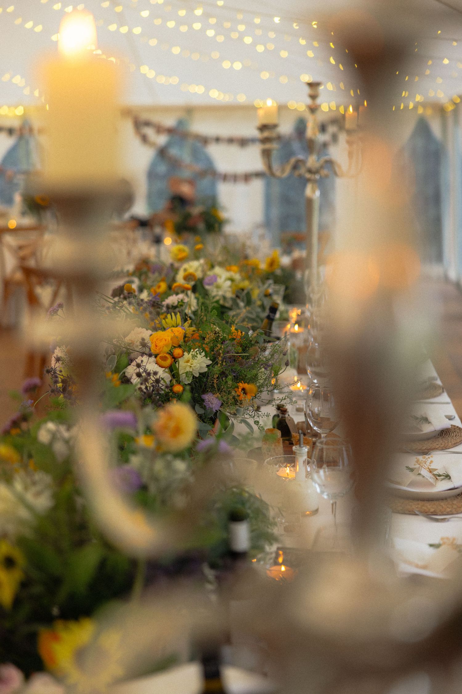 Soft focus view of wedding table decorations with twinkling lights and floral centerpieces.