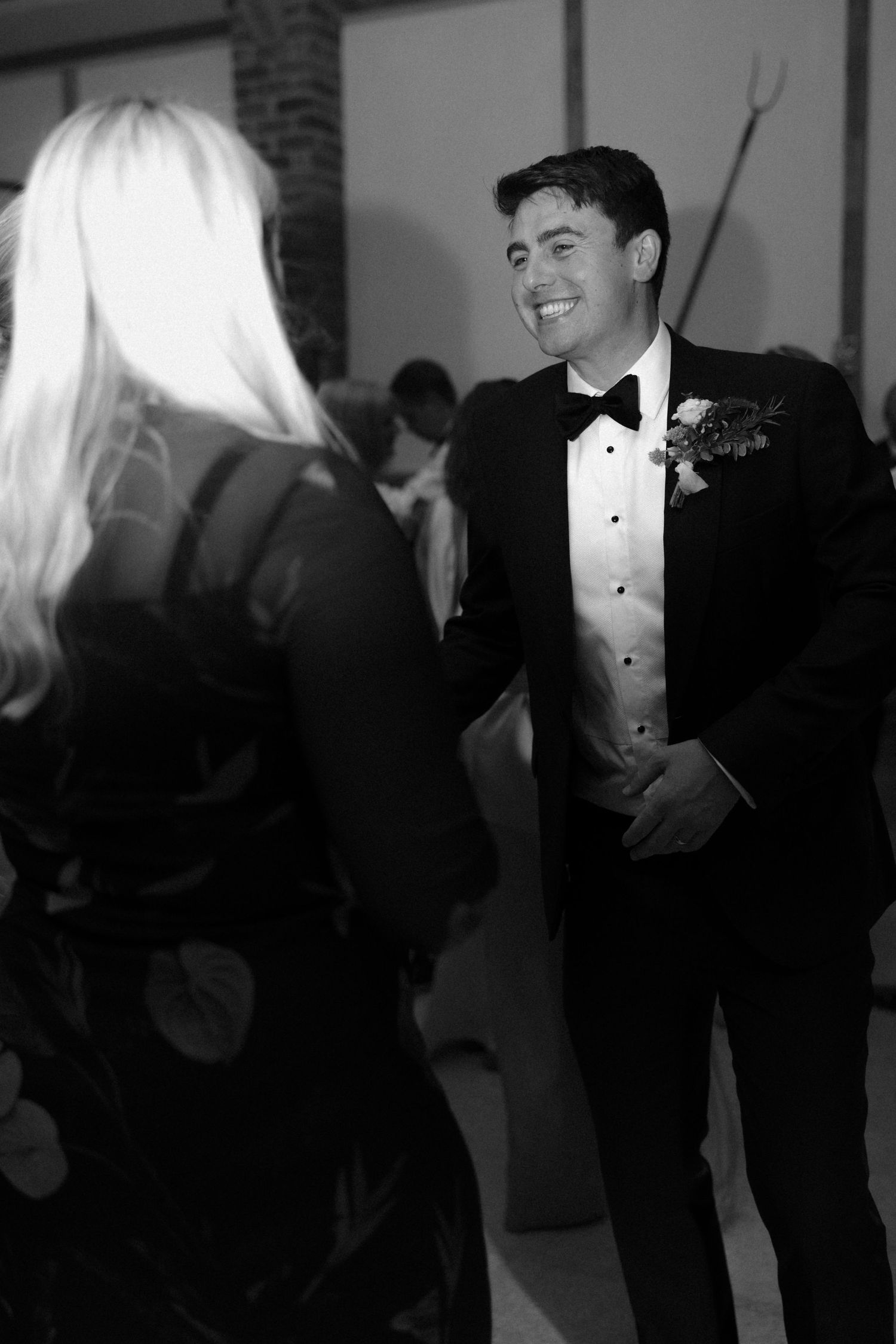 Formal wedding reception with guests in black tie attire mingling in venue.