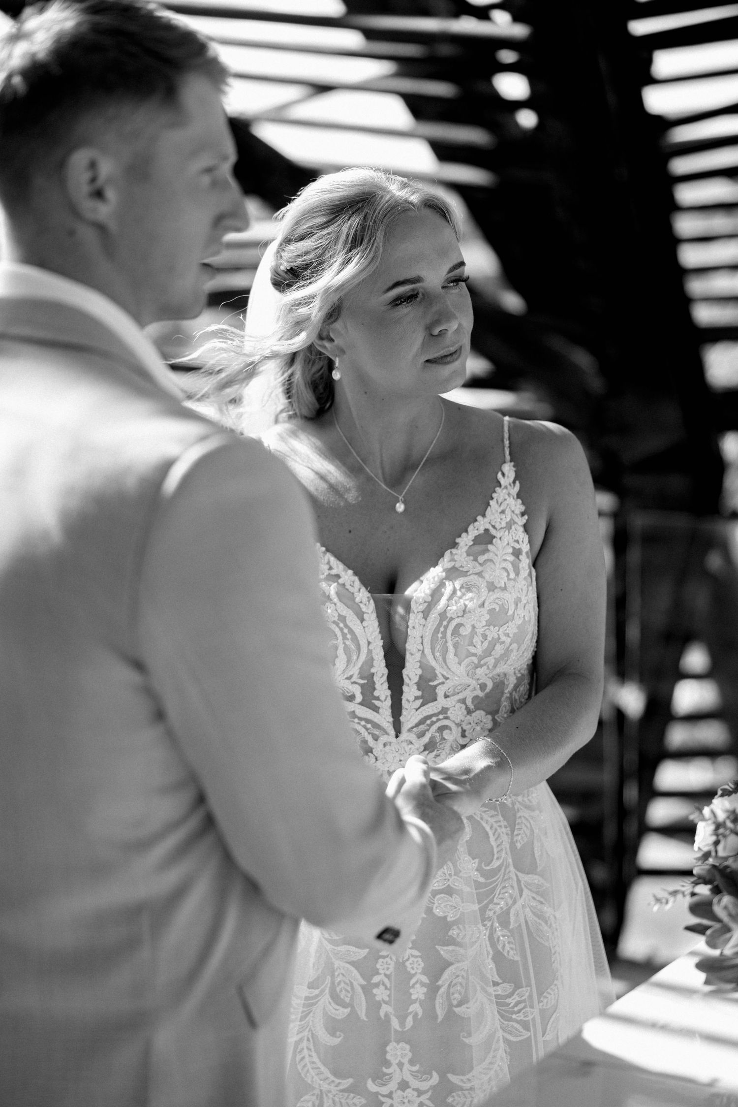 Black and white photo of wedding ceremony under geometric pergola structure.