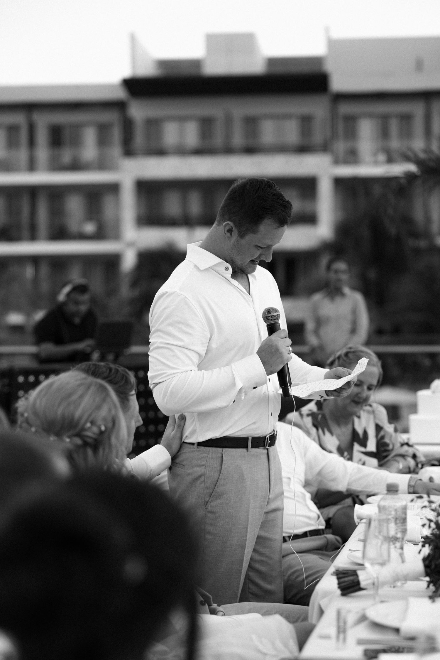 Black and white photo of guests giving speeches at an outdoor wedding reception.