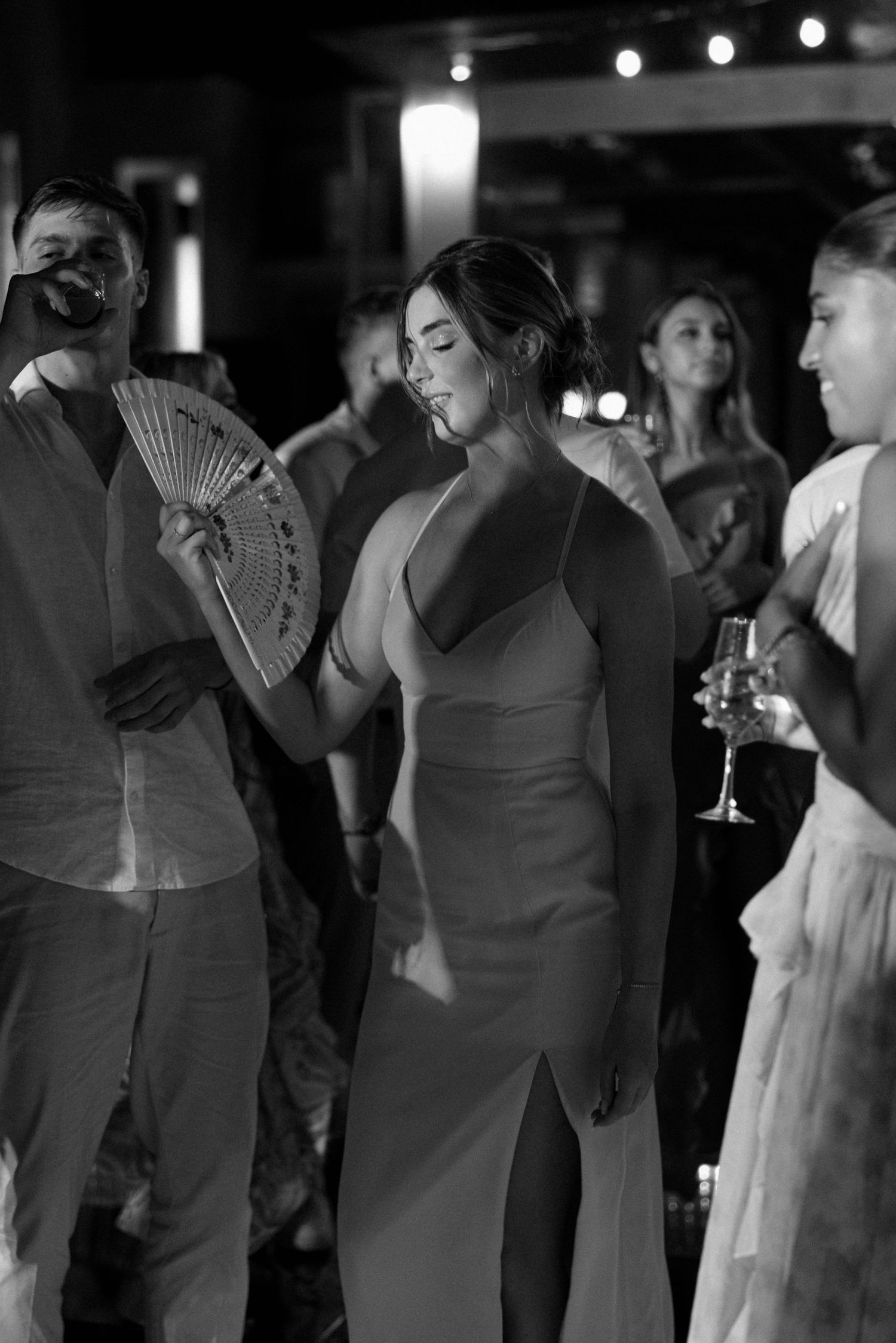 Wedding guests dancing and mingling at a dimly lit evening reception.